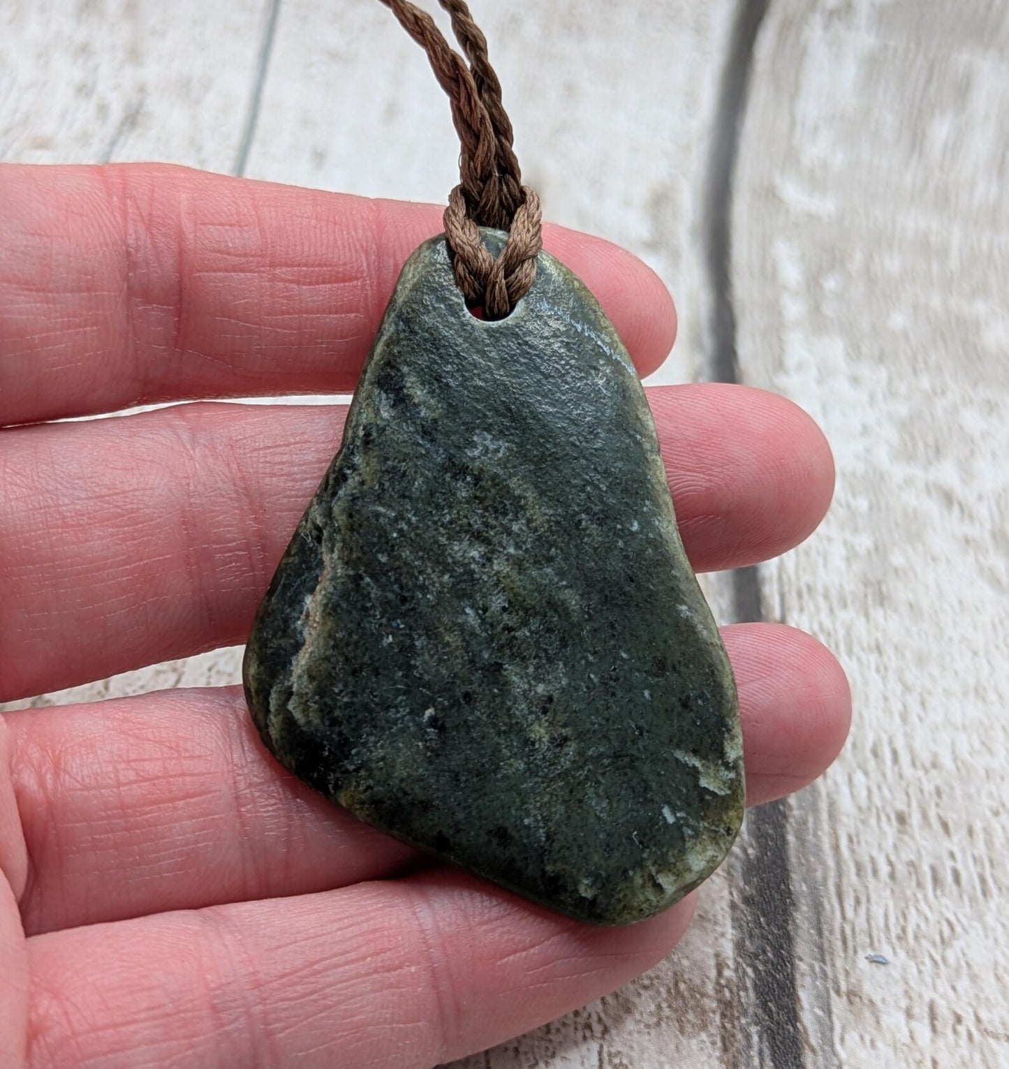 Tumbled polished New Zealand Pounamu greenstone pebble pendant.