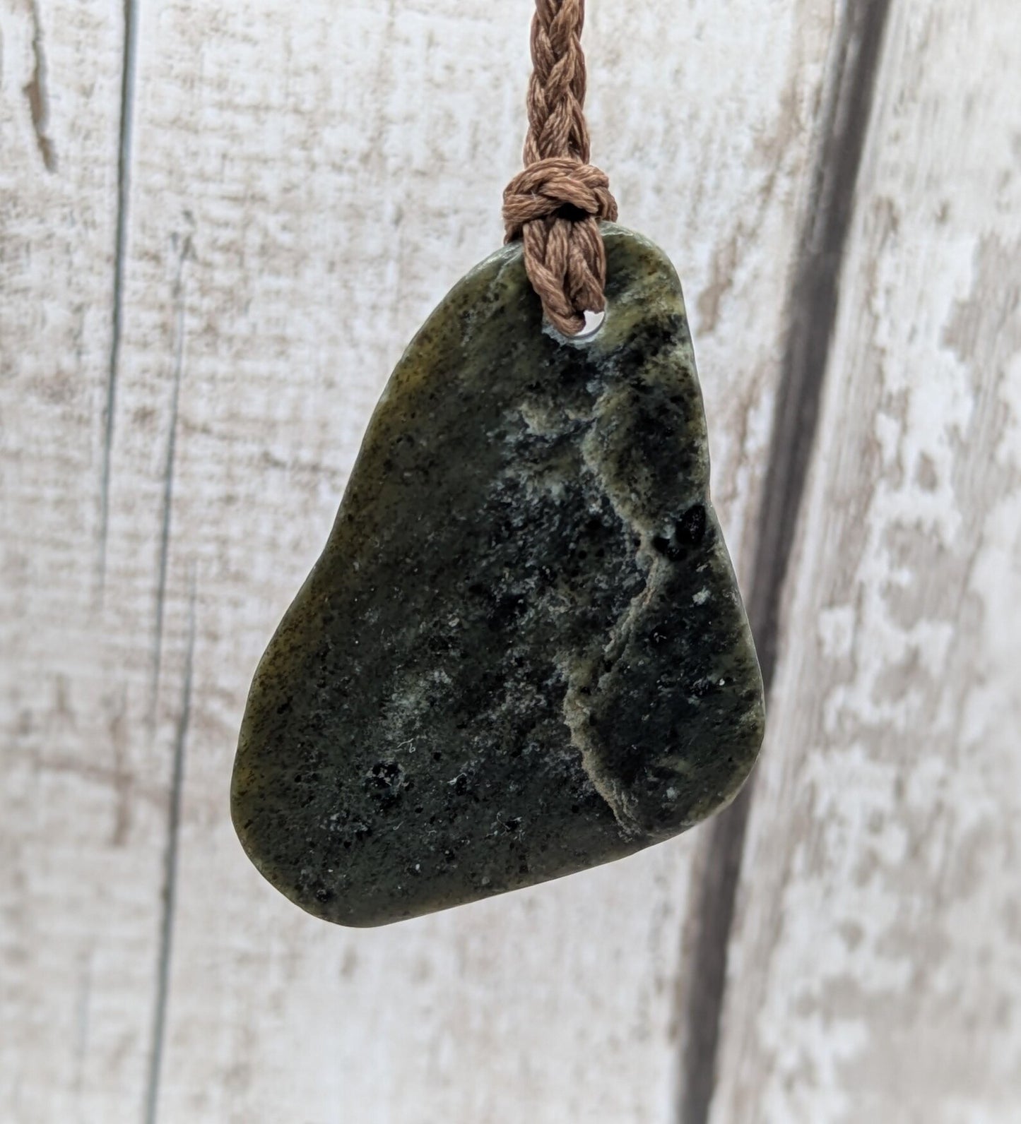 Tumbled polished New Zealand Pounamu greenstone pebble pendant.
