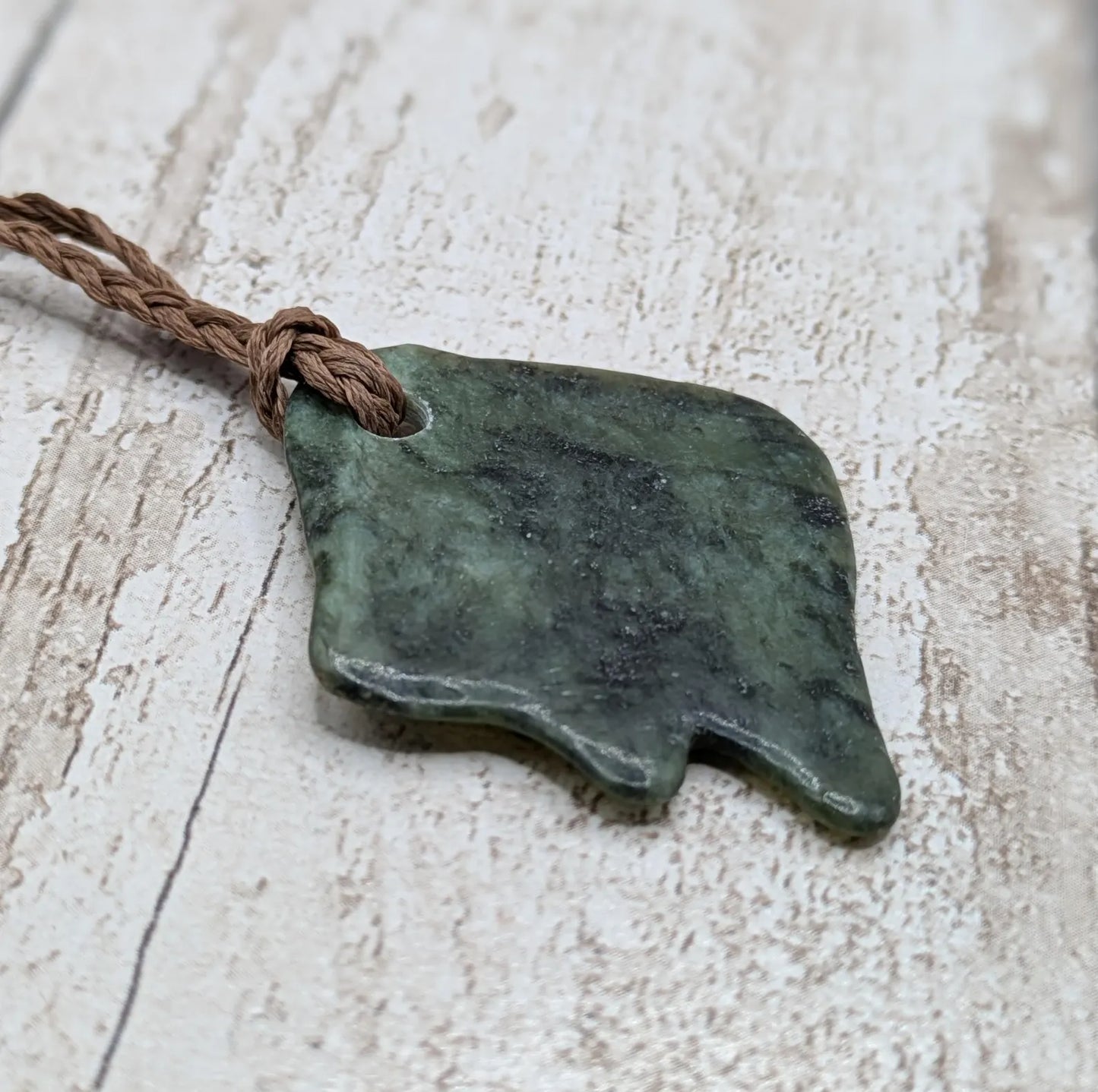 Tumble polished New Zealand Pounamu greenstone pebble pendant.