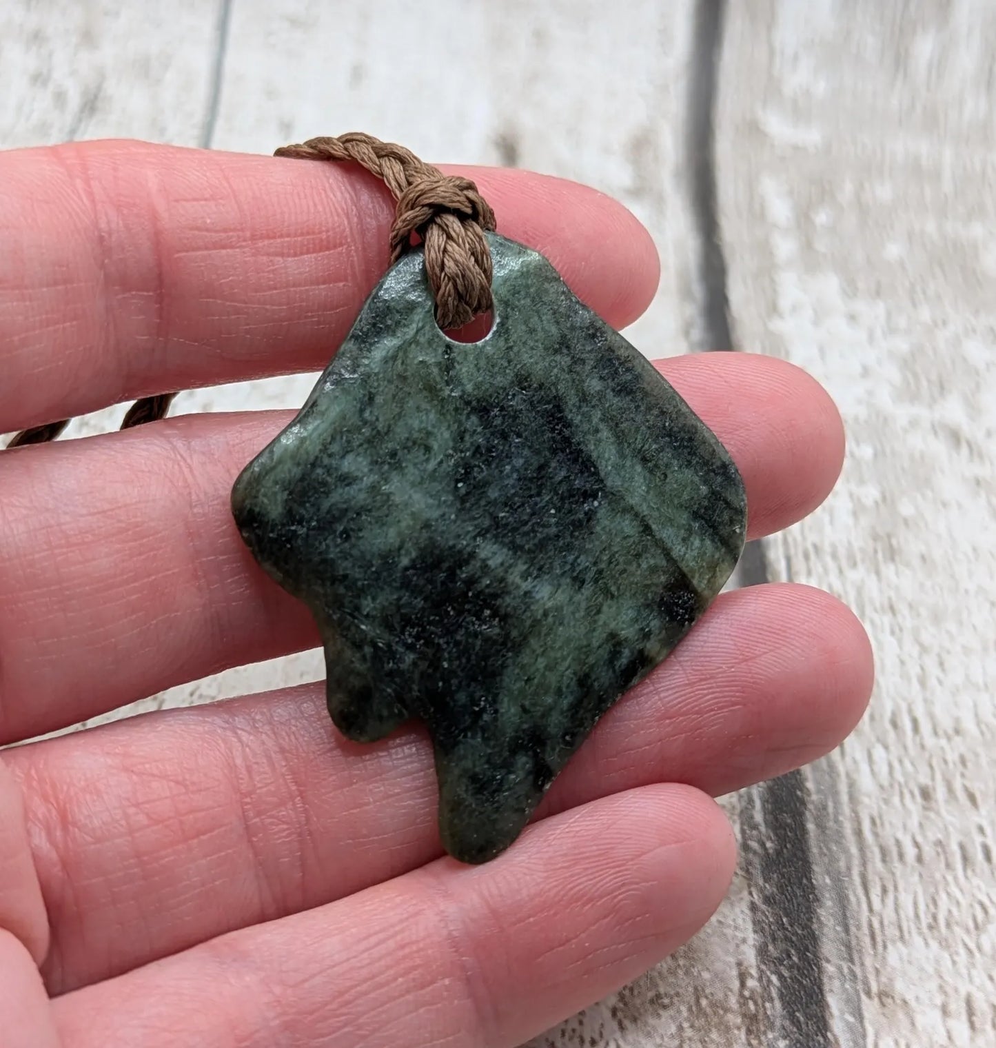 Tumble polished New Zealand Pounamu greenstone pebble pendant.
