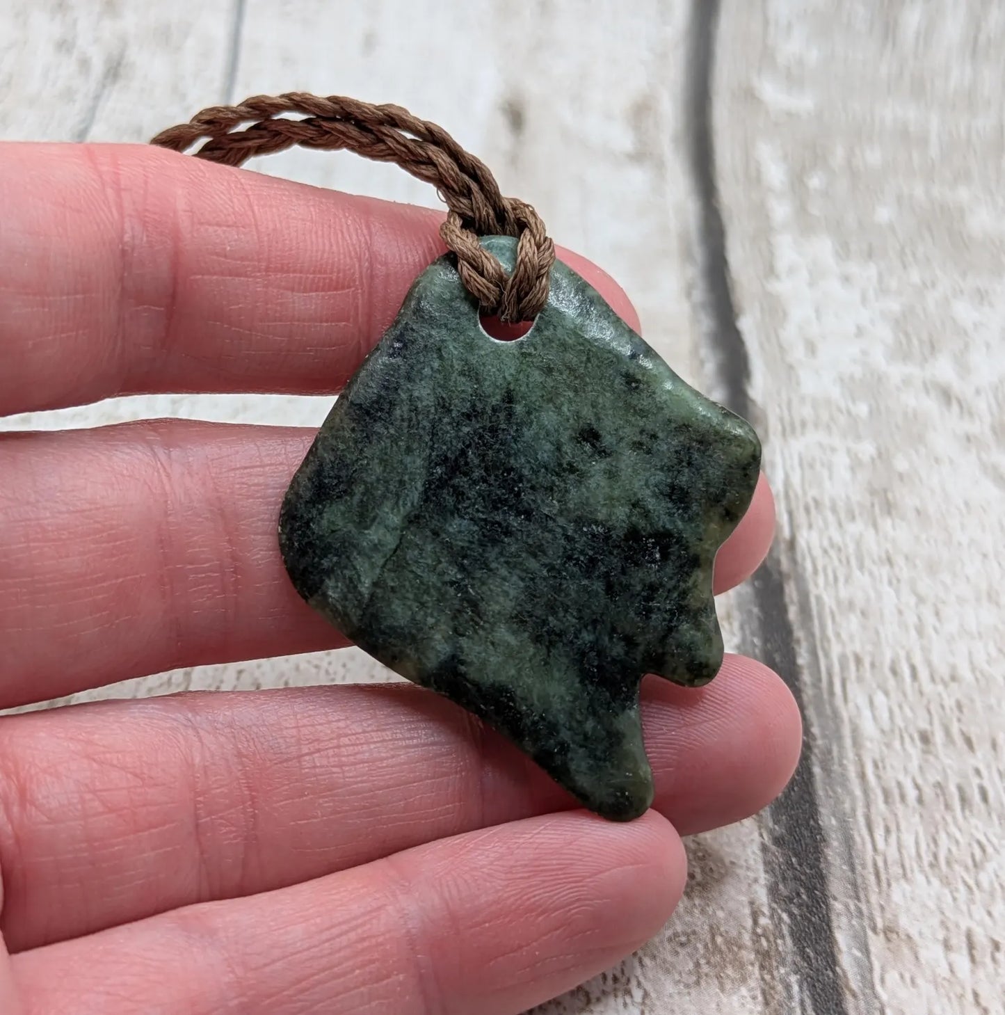 Tumble polished New Zealand Pounamu greenstone pebble pendant.