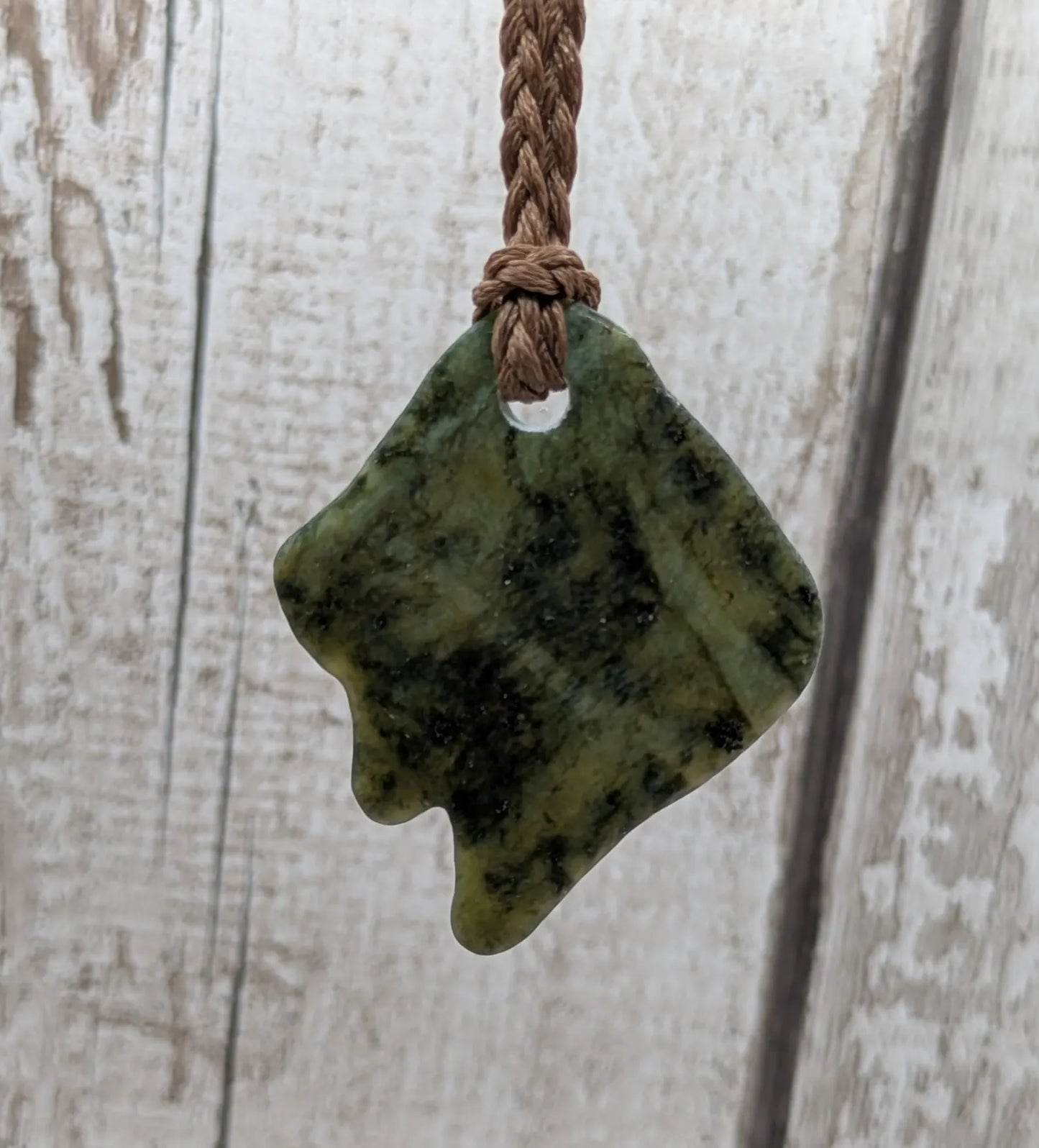 Tumble polished New Zealand Pounamu greenstone pebble pendant.