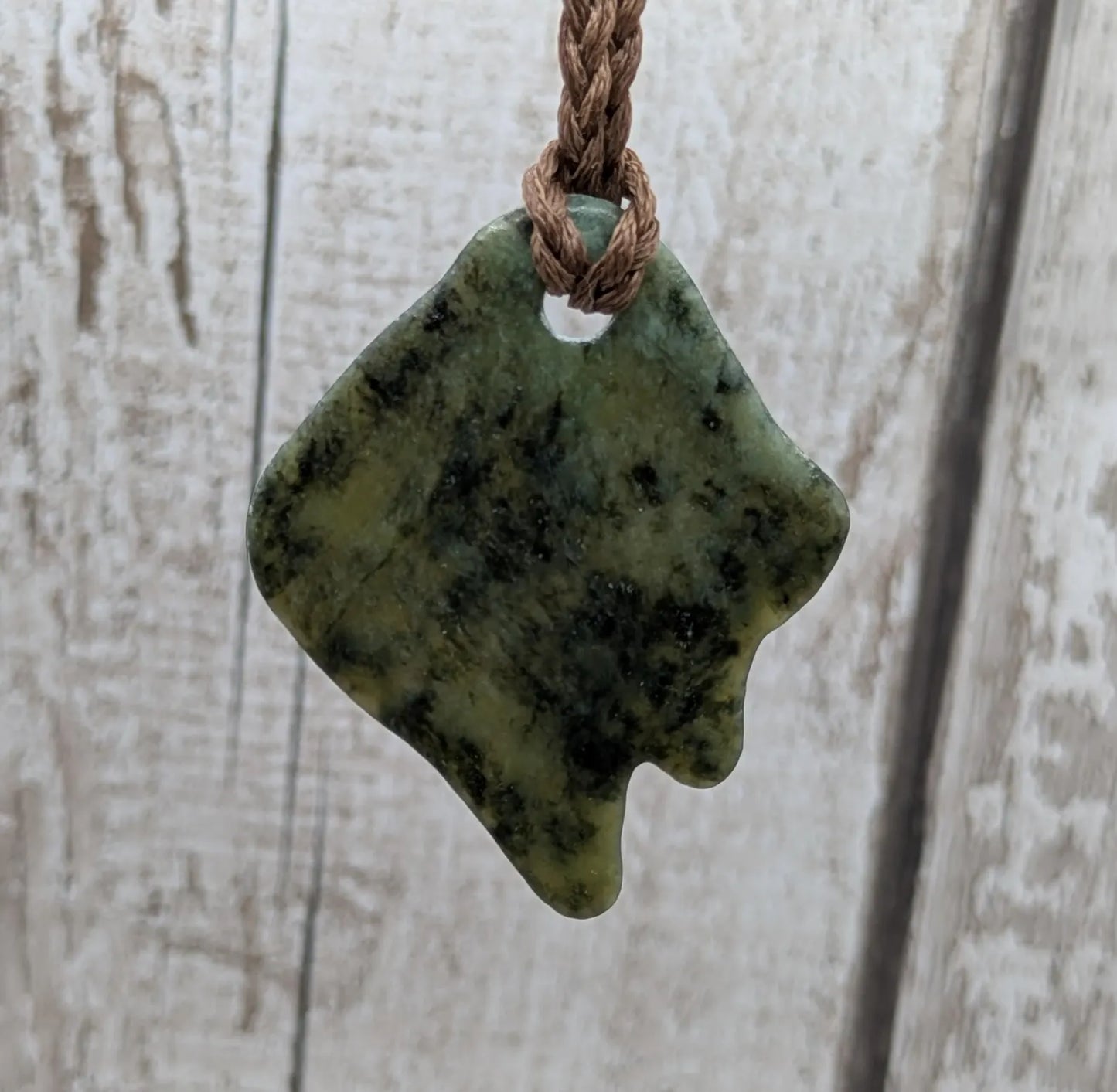 Tumble polished New Zealand Pounamu greenstone pebble pendant.