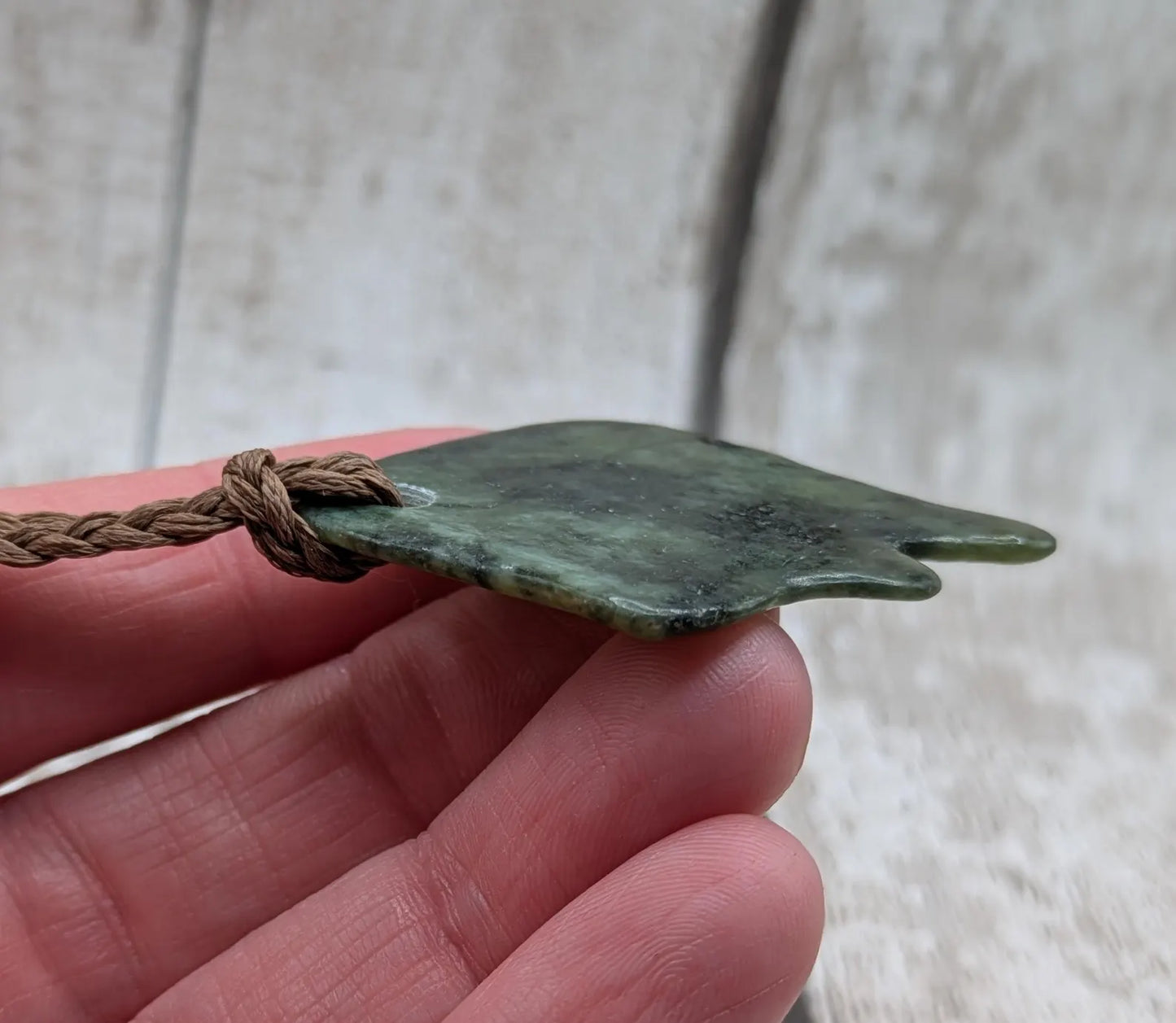 Tumble polished New Zealand Pounamu greenstone pebble pendant.