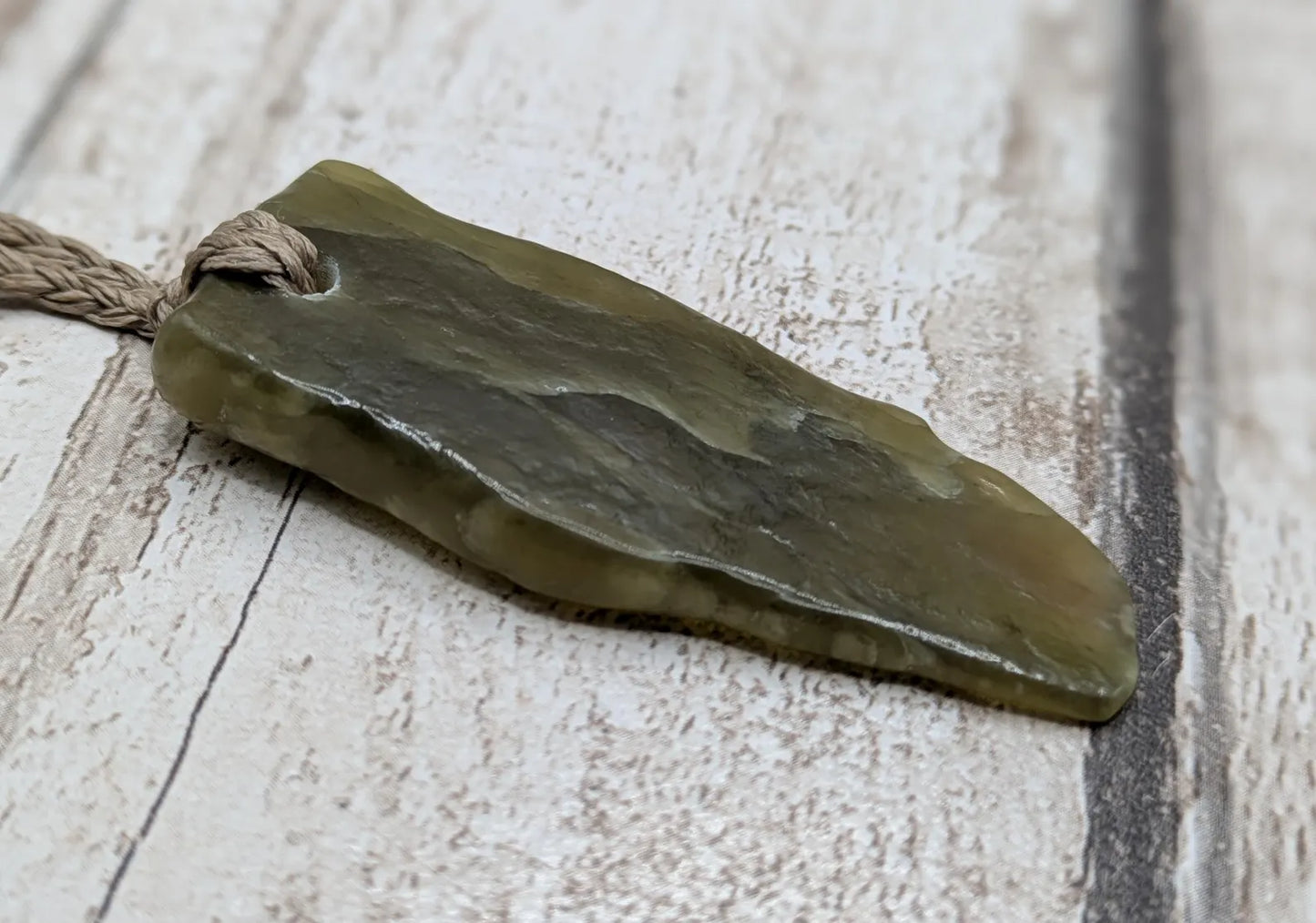 Tumble polished New Zealand Pounamu greenstone jade pendant.