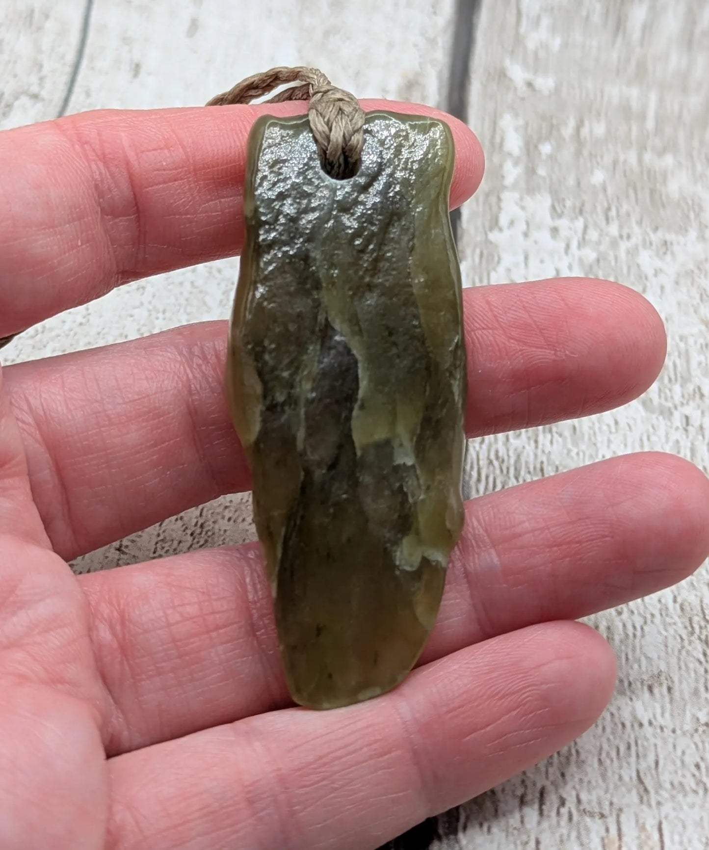 Tumble polished New Zealand Pounamu greenstone jade pendant.