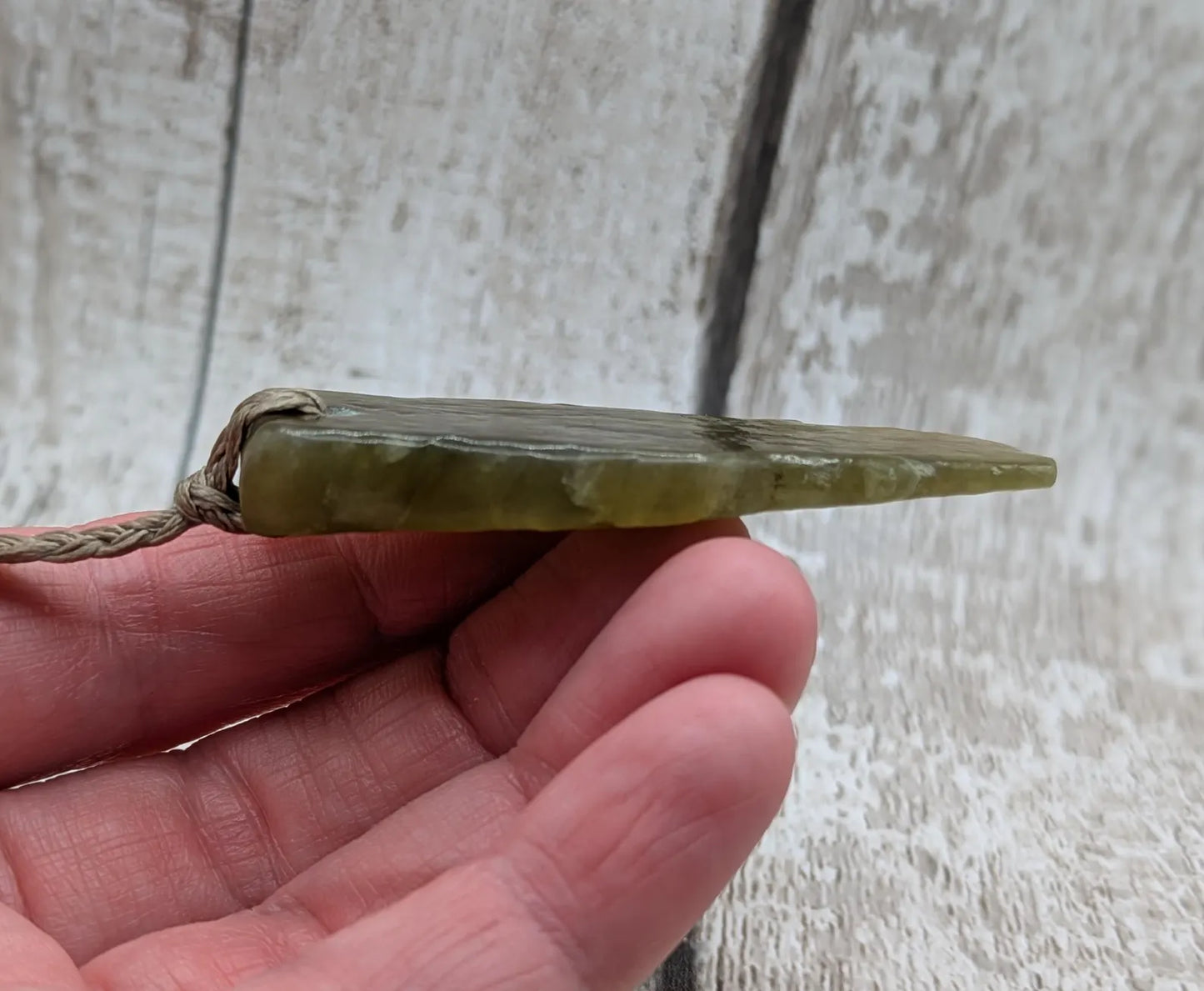 Tumble polished New Zealand Pounamu greenstone jade pendant.