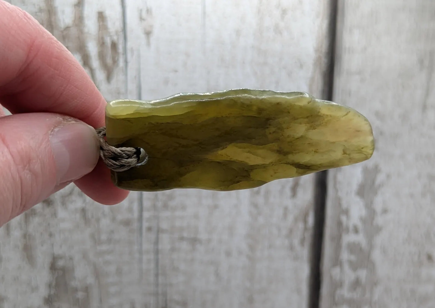 Tumble polished New Zealand Pounamu greenstone jade pendant.