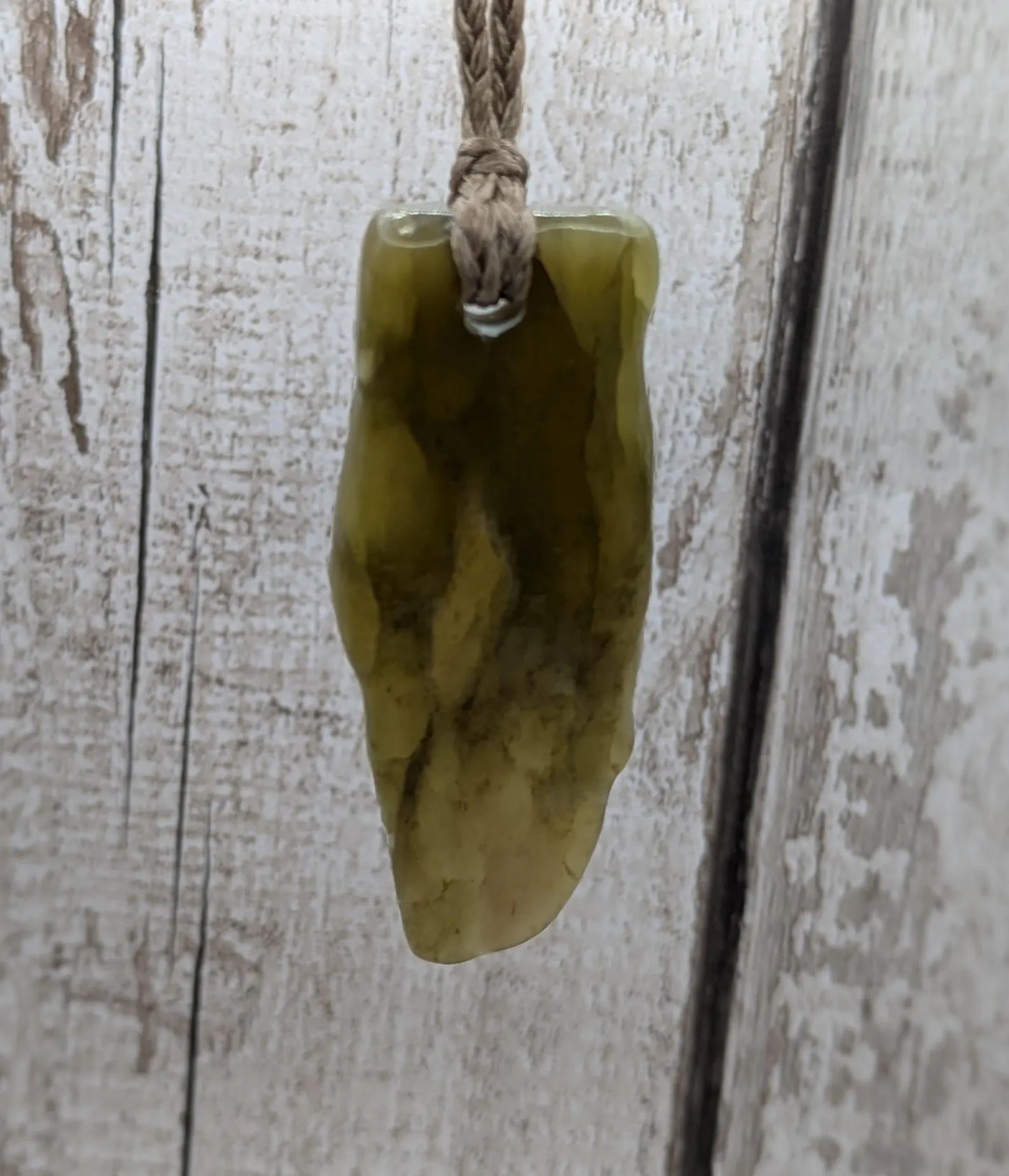 Tumble polished New Zealand Pounamu greenstone jade pendant.