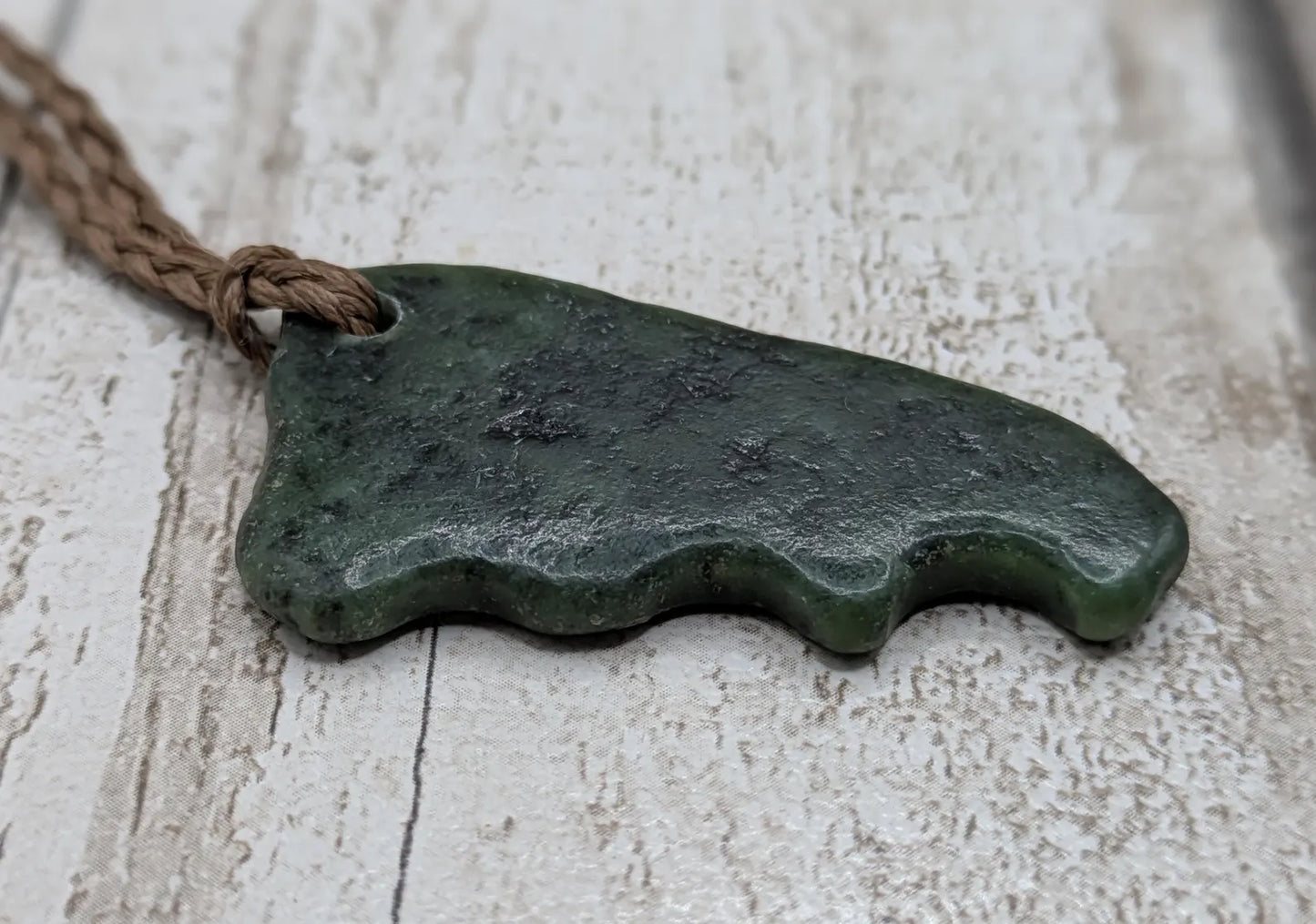 Tumble polished New Zealand Pounamu greenstone jade pendant.