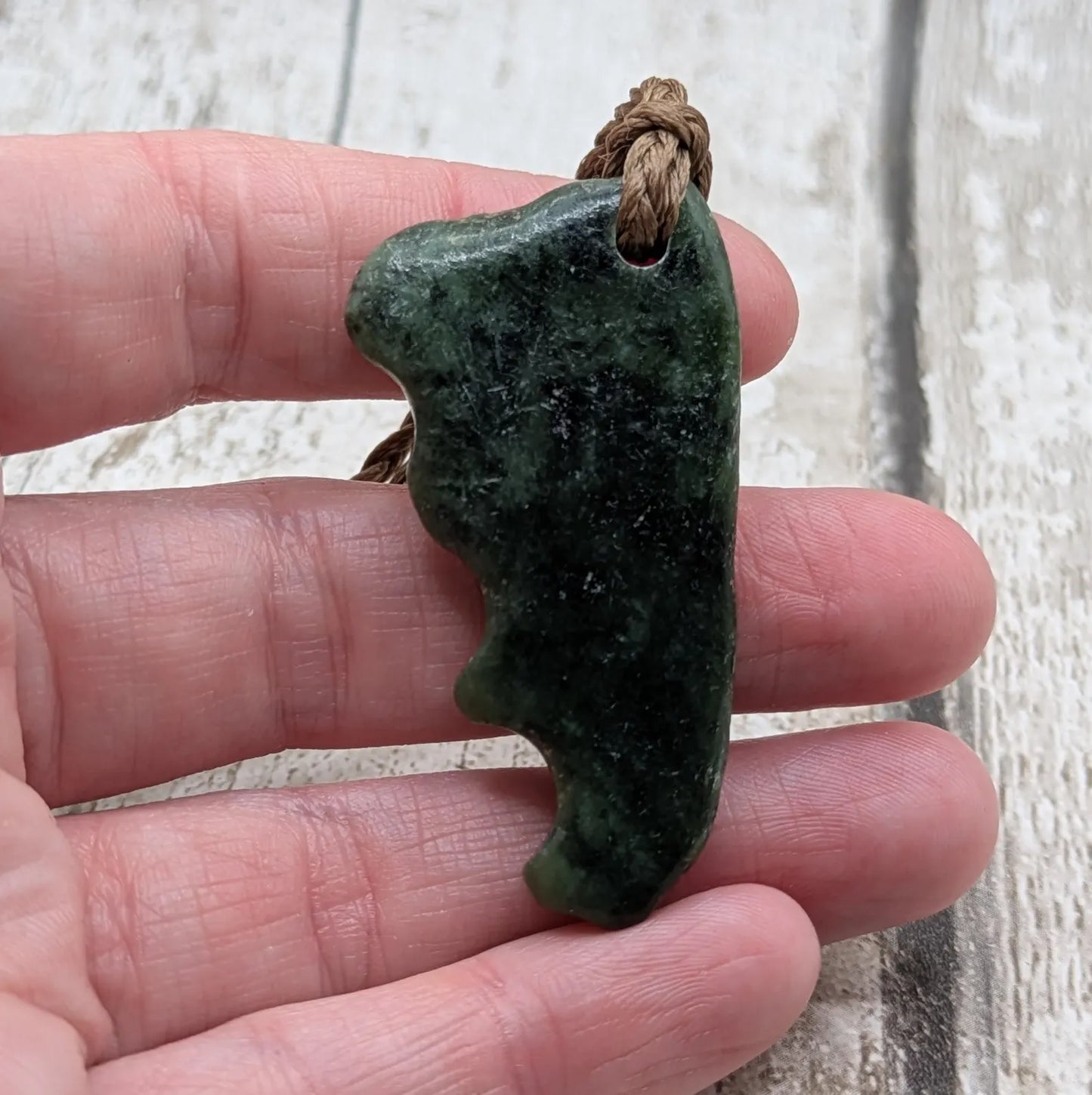 Tumble polished New Zealand Pounamu greenstone jade pendant.