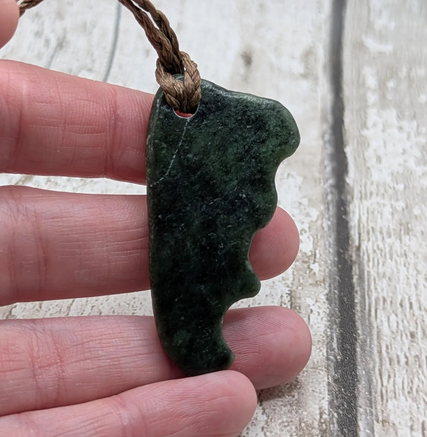 Tumble polished New Zealand Pounamu greenstone jade pendant.