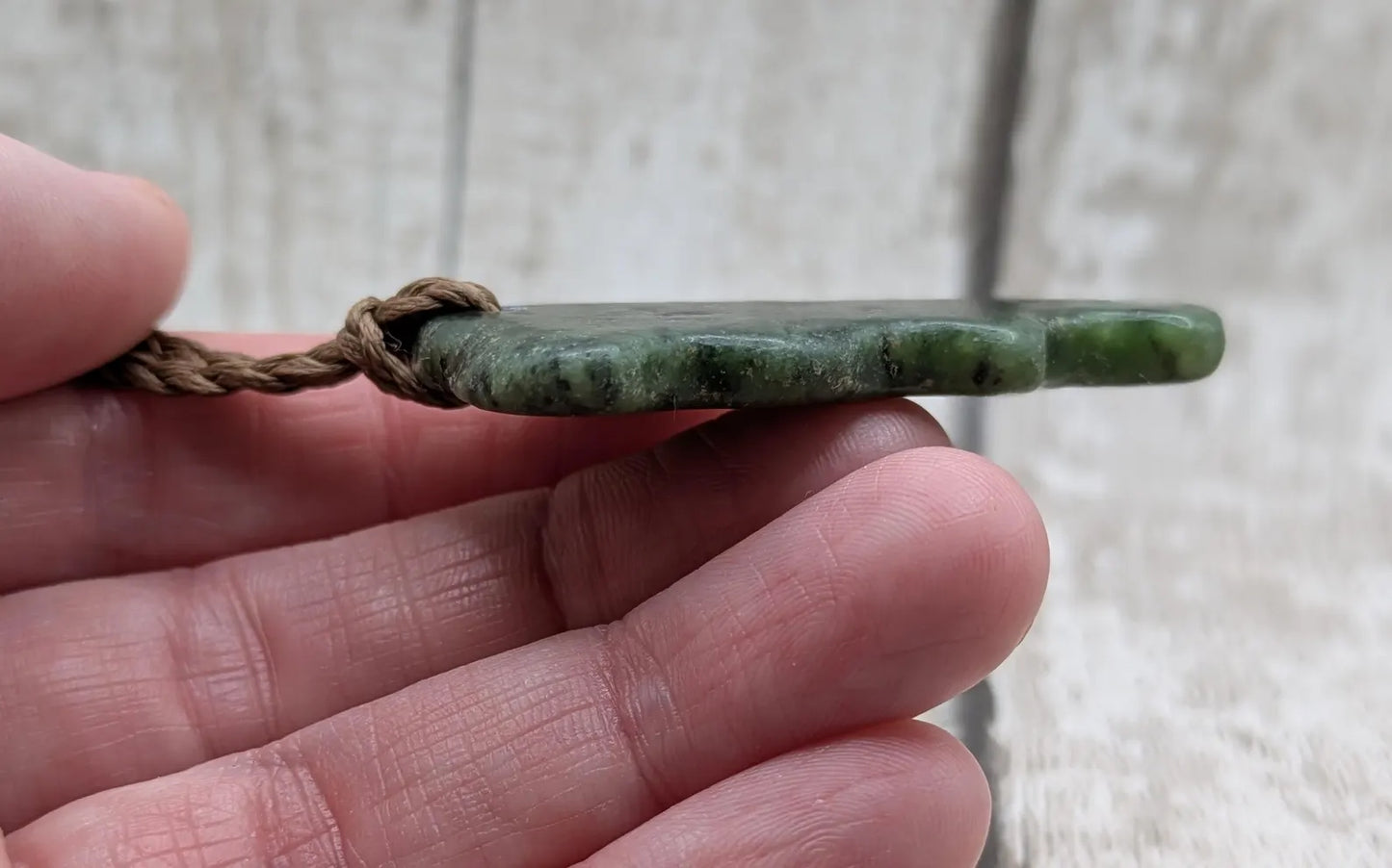 Tumble polished New Zealand Pounamu greenstone jade pendant.