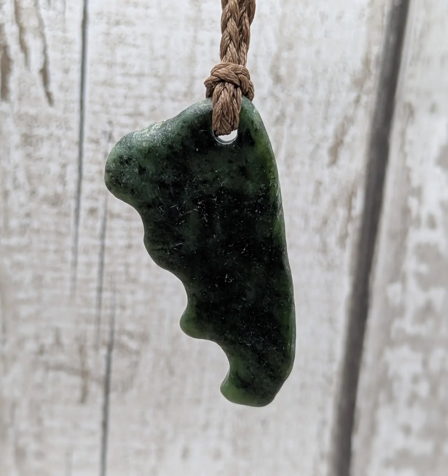Tumble polished New Zealand Pounamu greenstone jade pendant.