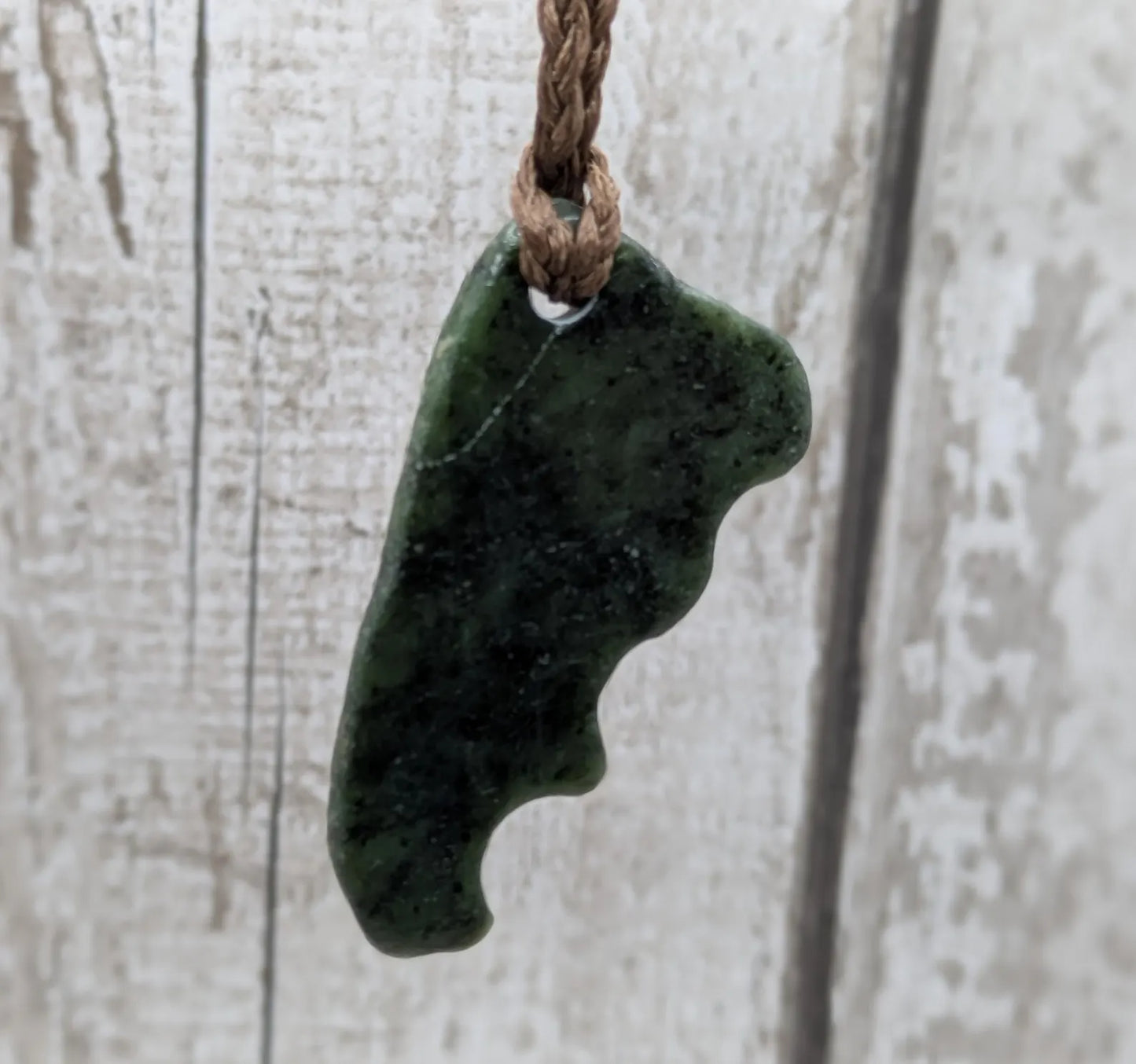 Tumble polished New Zealand Pounamu greenstone jade pendant.