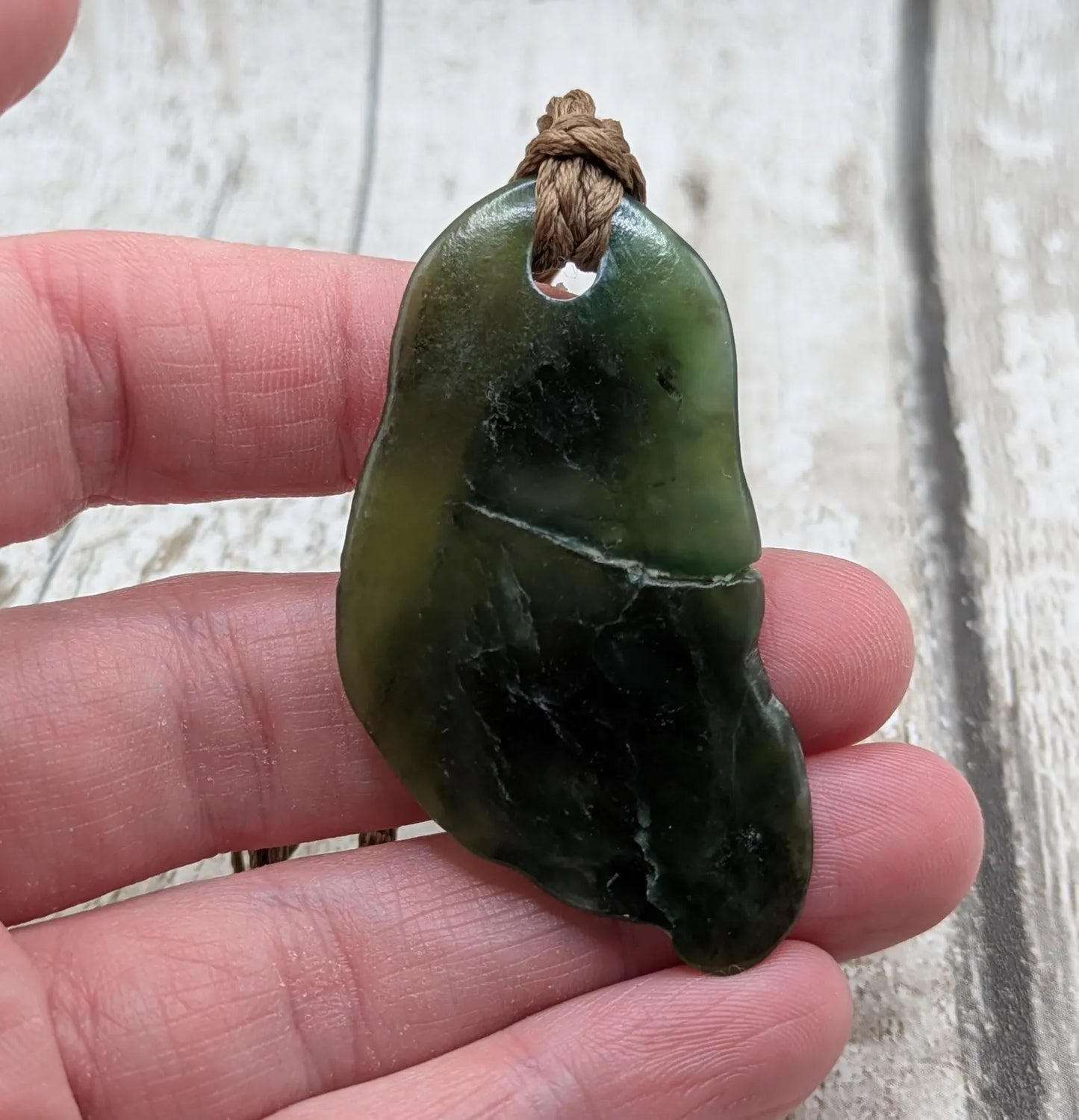 Tumbled polished New Zealand greenstone Pounamu jade pendant.