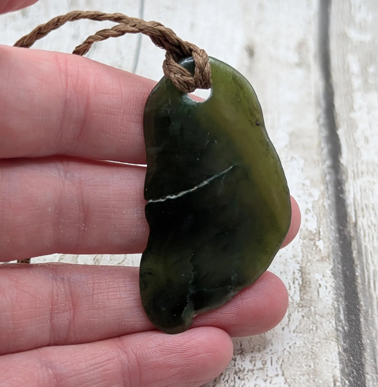 Tumbled polished New Zealand greenstone Pounamu jade pendant.