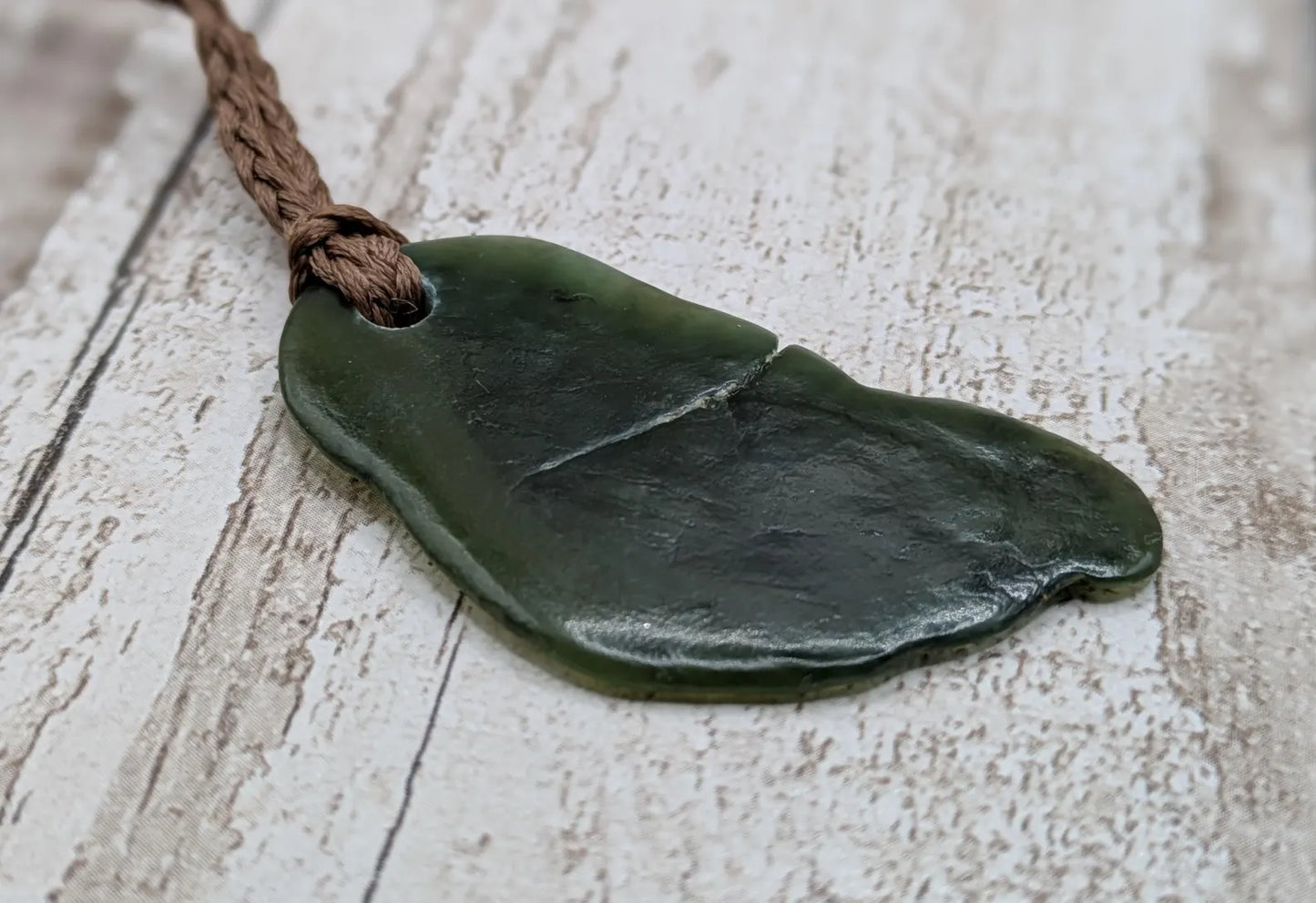 Tumbled polished New Zealand greenstone Pounamu jade pendant.