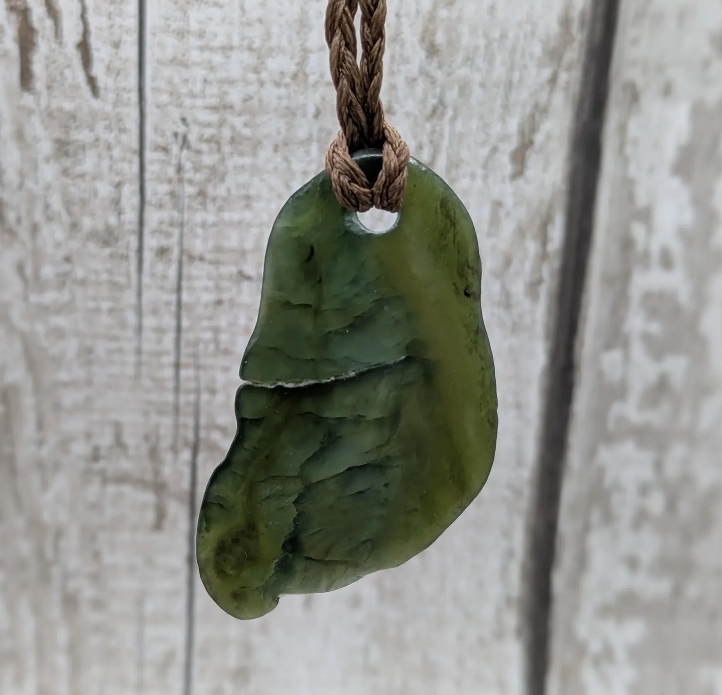 Tumbled polished New Zealand greenstone Pounamu jade pendant.