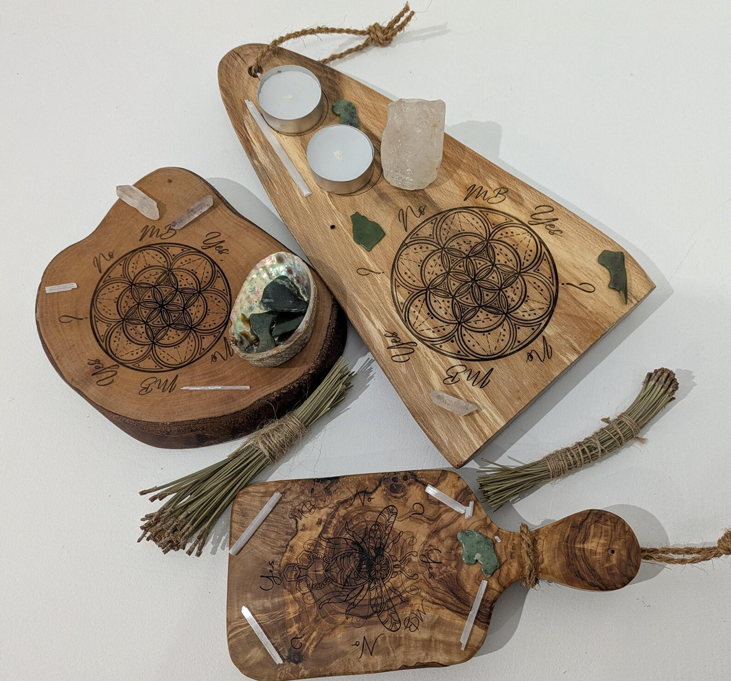 Wooden tree slice dowsing board with geometric laser print design, incense stick holder and loose abalone shell for crystals and herbs.