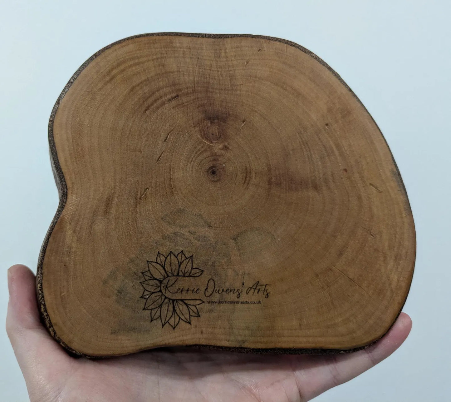 Wooden tree slice dowsing board with geometric laser print design, incense stick holder and loose abalone shell for crystals and herbs.