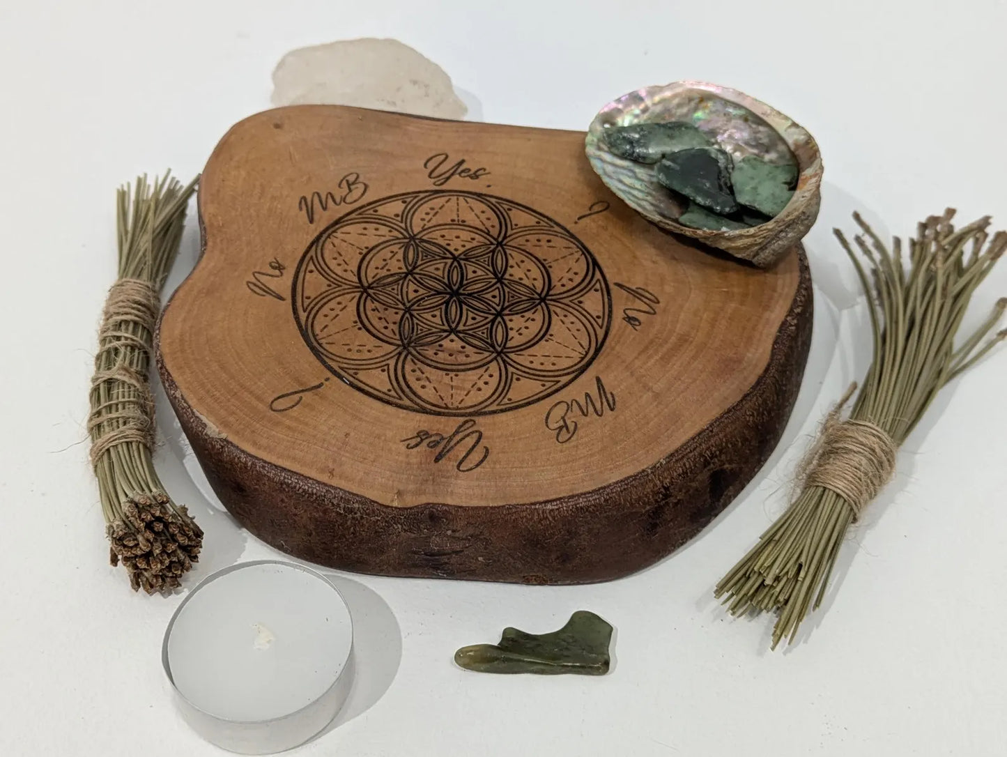 Wooden tree slice dowsing board with geometric laser print design, incense stick holder and loose abalone shell for crystals and herbs.
