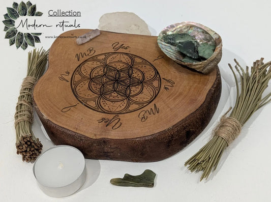 Wooden tree slice dowsing board with geometric laser print design, incense stick holder and loose abalone shell for crystals and herbs.