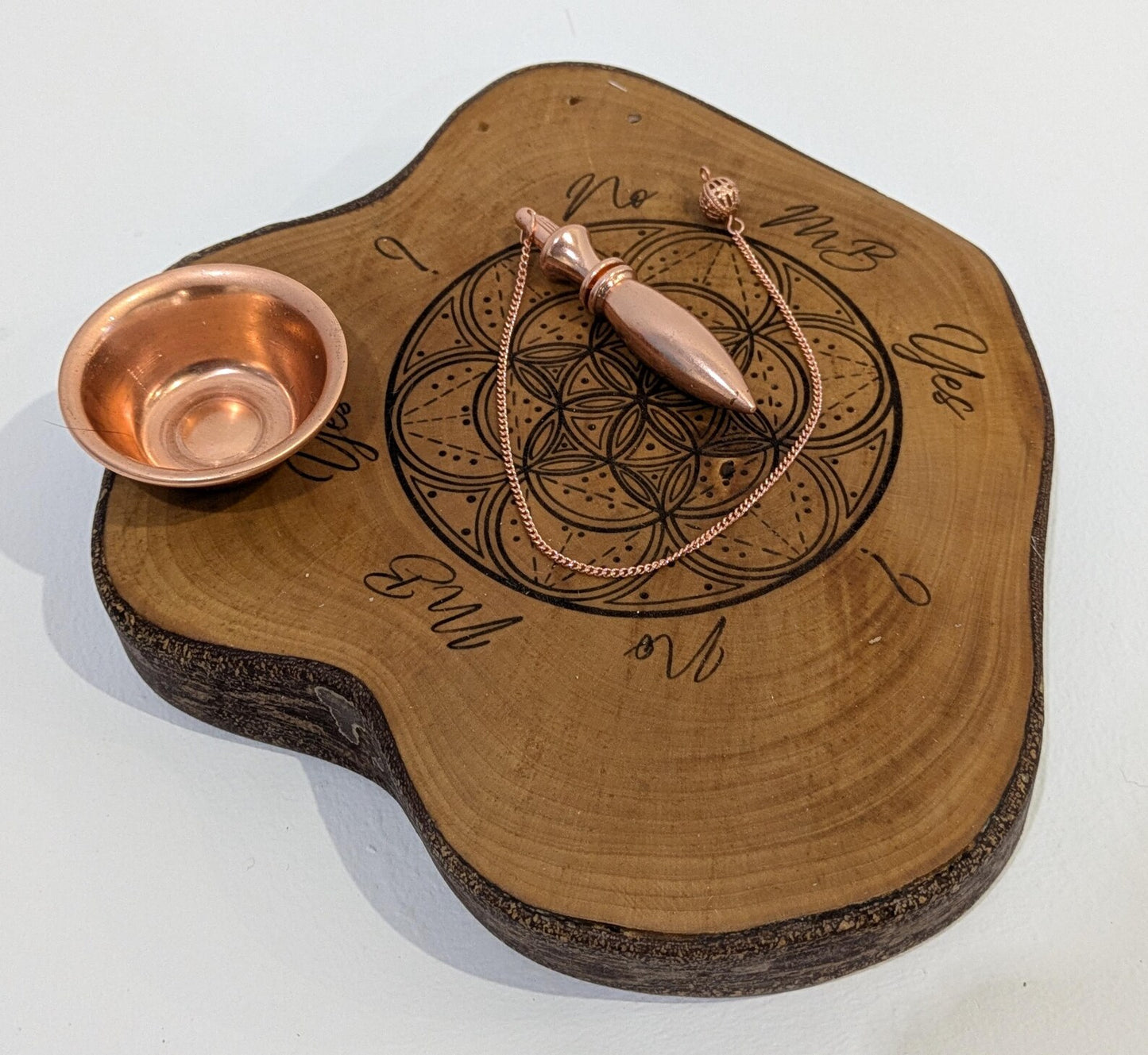 Random wood slice pendulum dowsing board with geometric laser print.