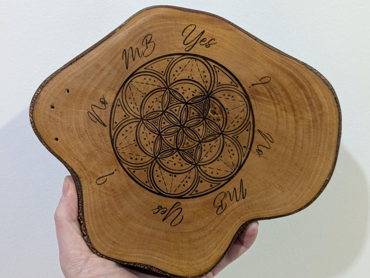 Random wood slice pendulum dowsing board with geometric laser print.