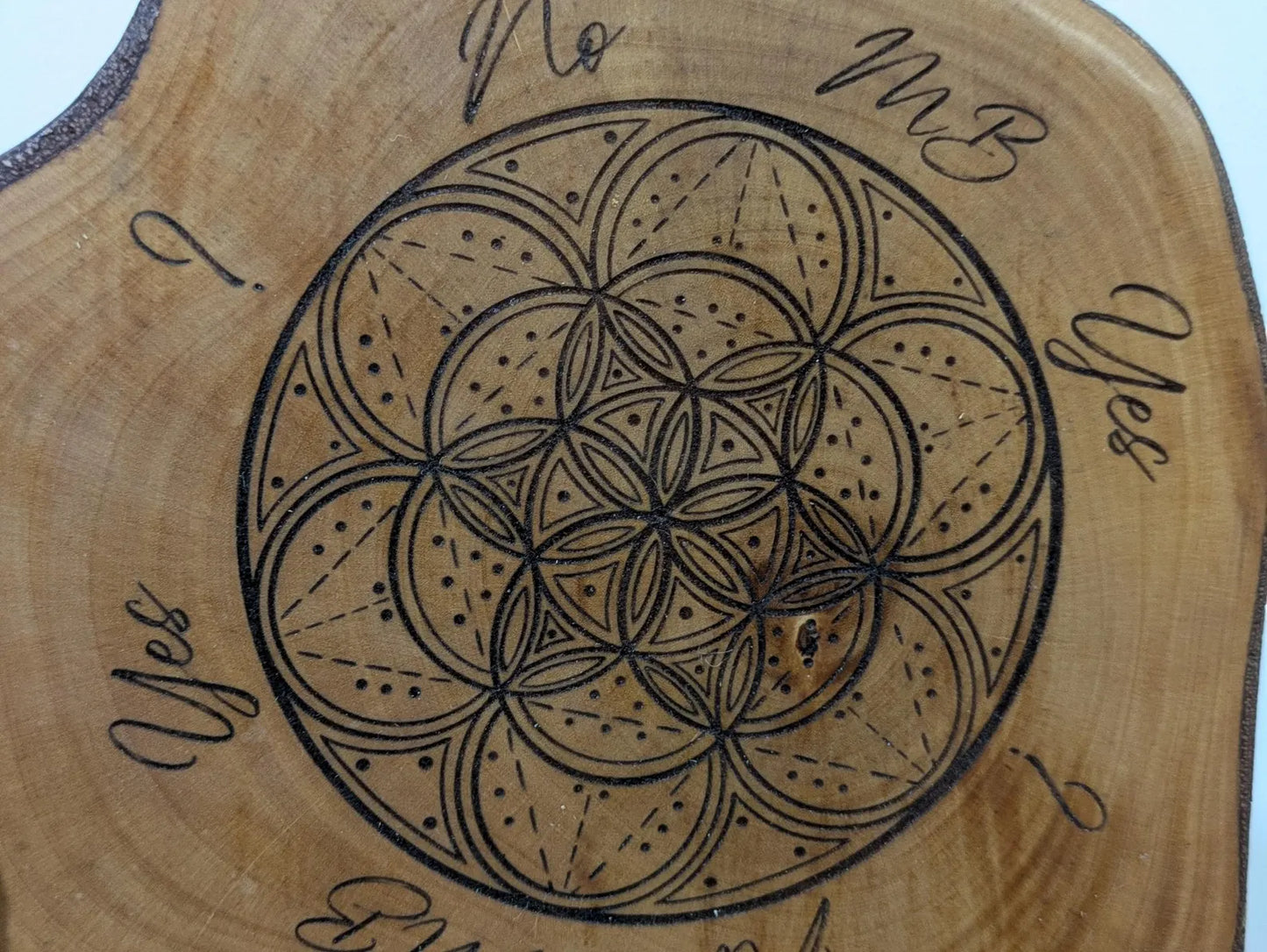 Random wood slice pendulum dowsing board with geometric laser print.