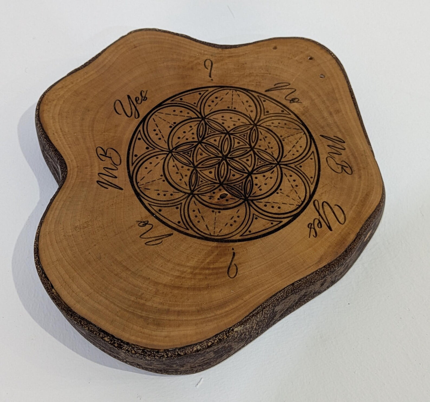 Random wood slice pendulum dowsing board with geometric laser print.
