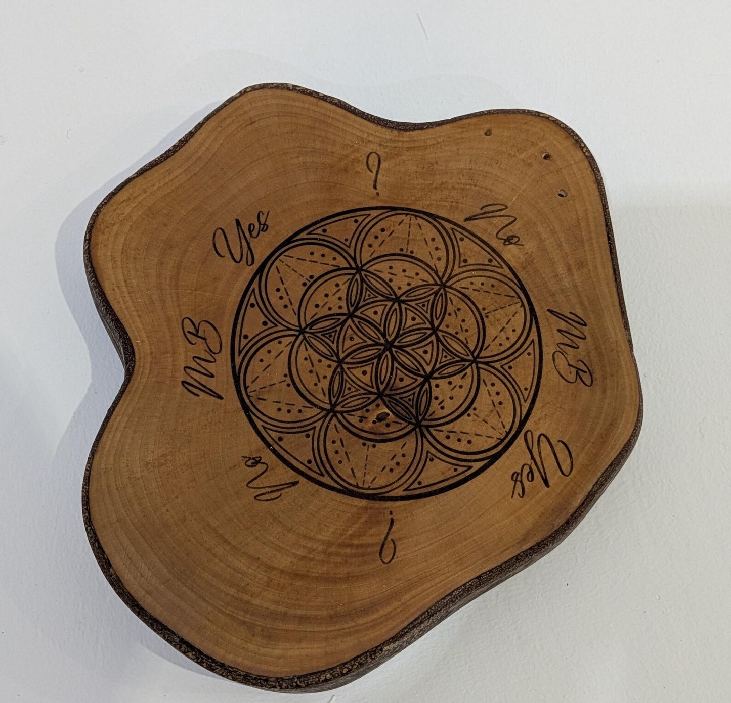 Random wood slice pendulum dowsing board with geometric laser print.