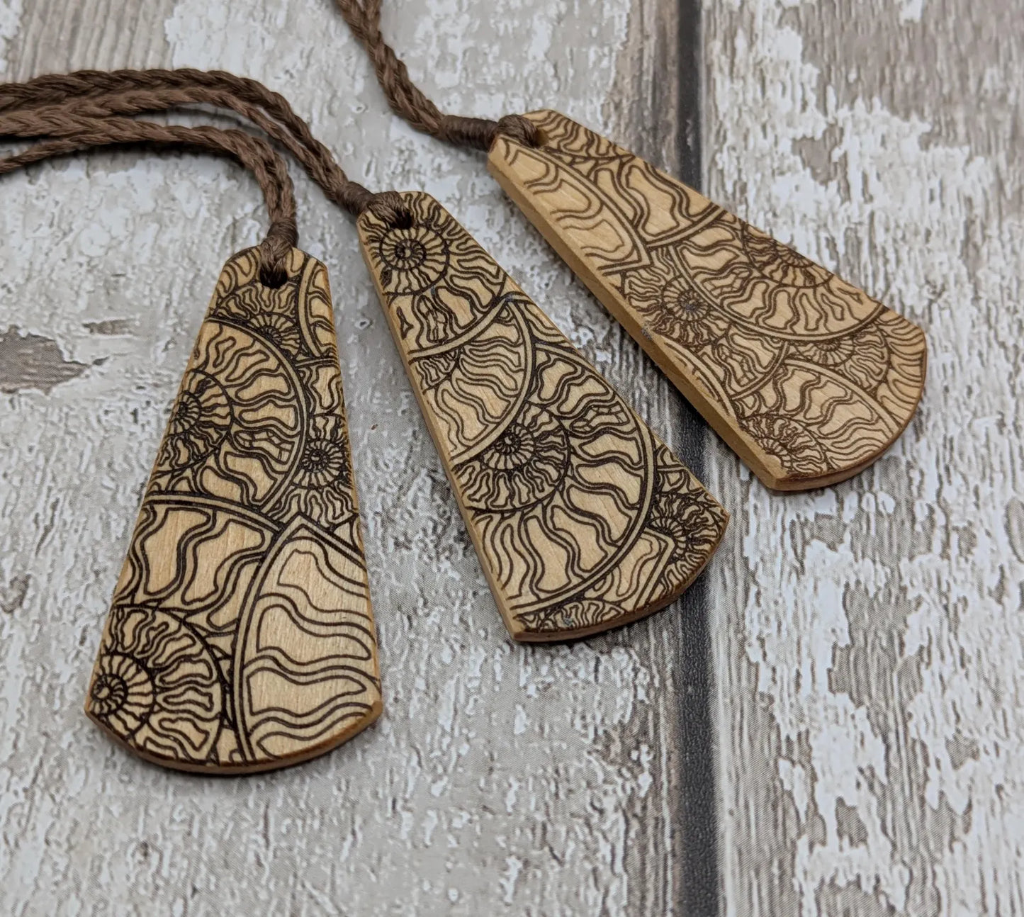 Wooden roimata pendant with laser print layered ammonite design.