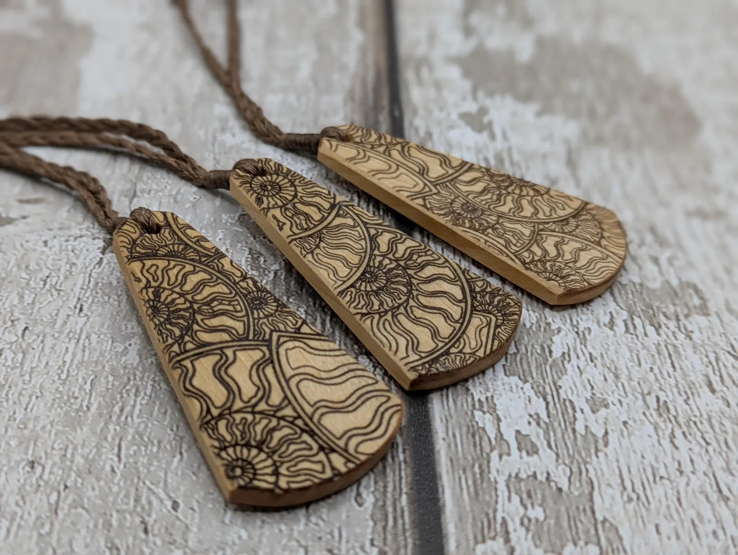 Wooden roimata pendant with laser print layered ammonite design.