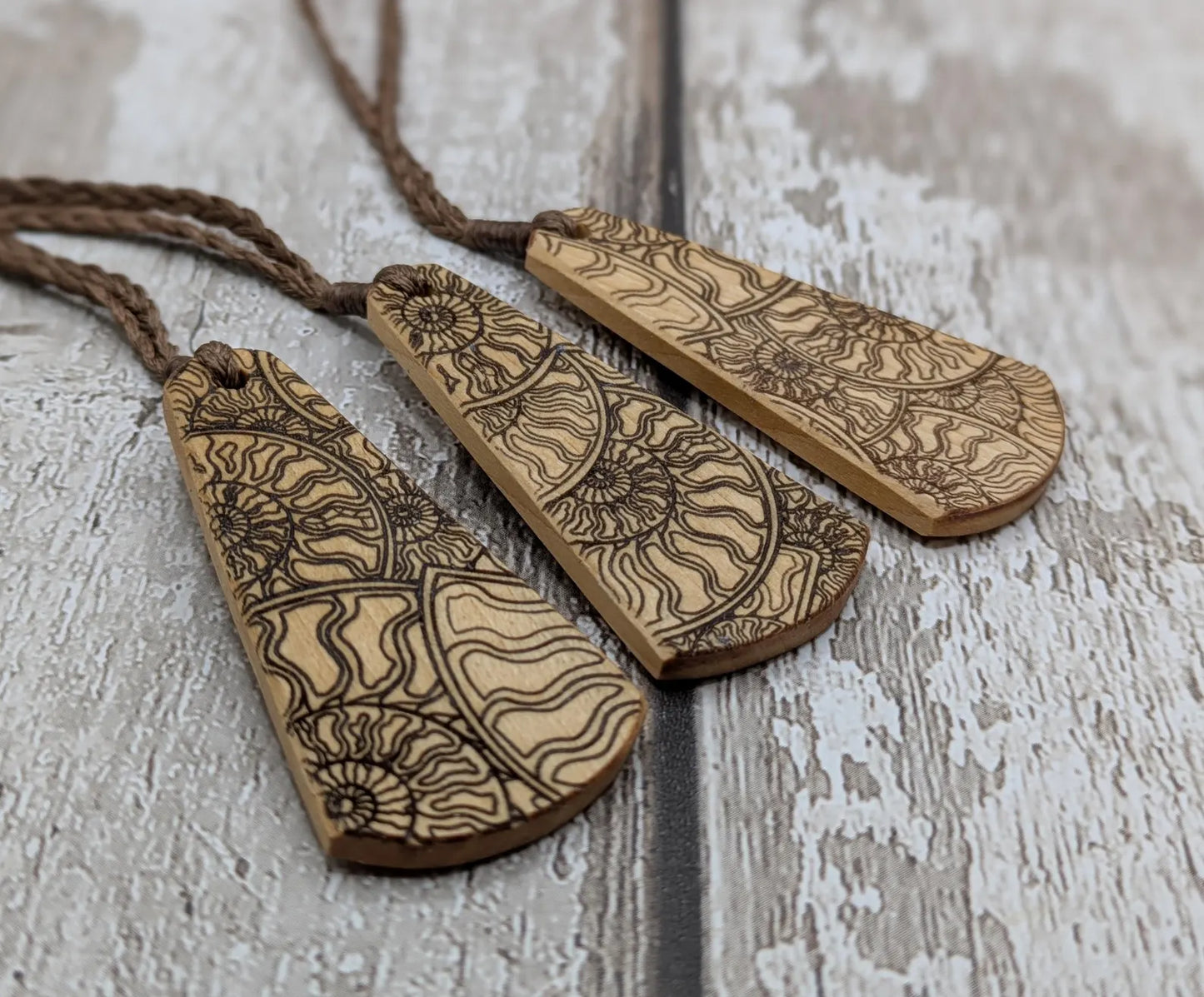 Wooden roimata pendant with laser print layered ammonite design.