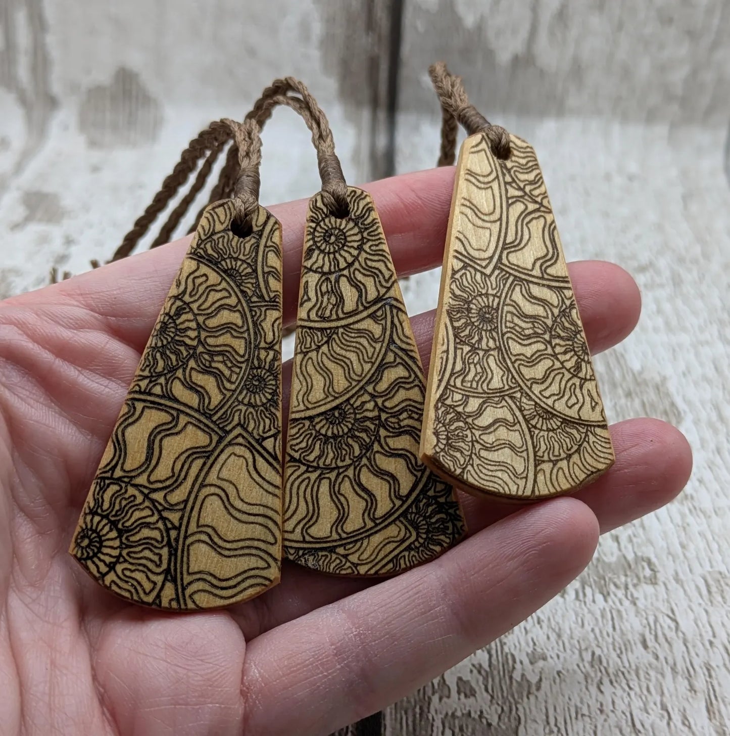 Wooden roimata pendant with laser print layered ammonite design.
