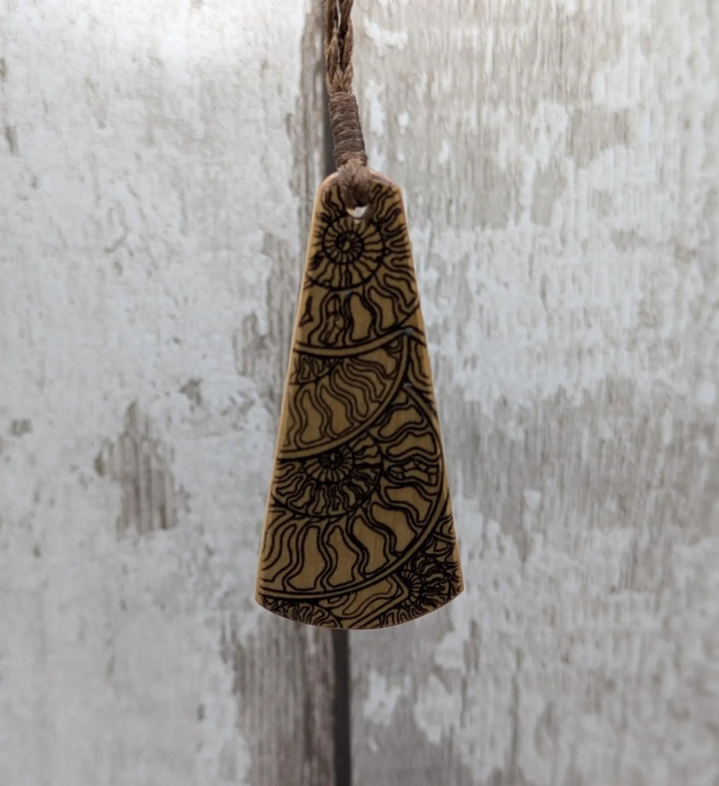 Wooden roimata pendant with laser print layered ammonite design.