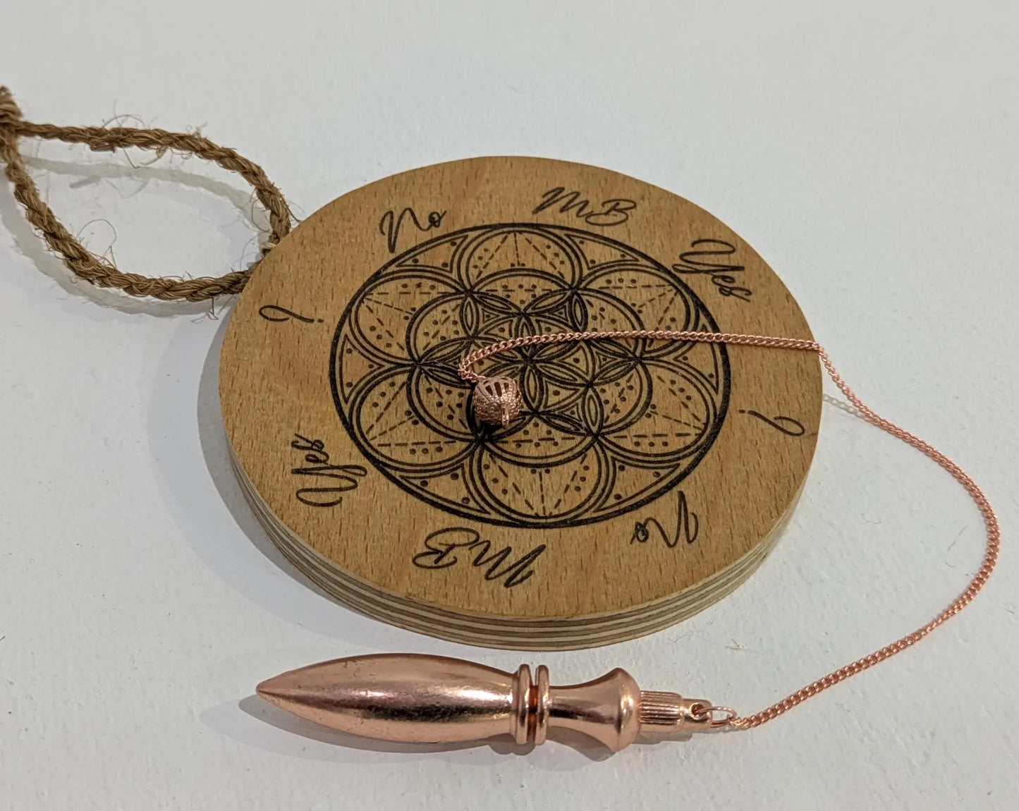 Recycled ply wood pendulum dowsing board with geometric design.