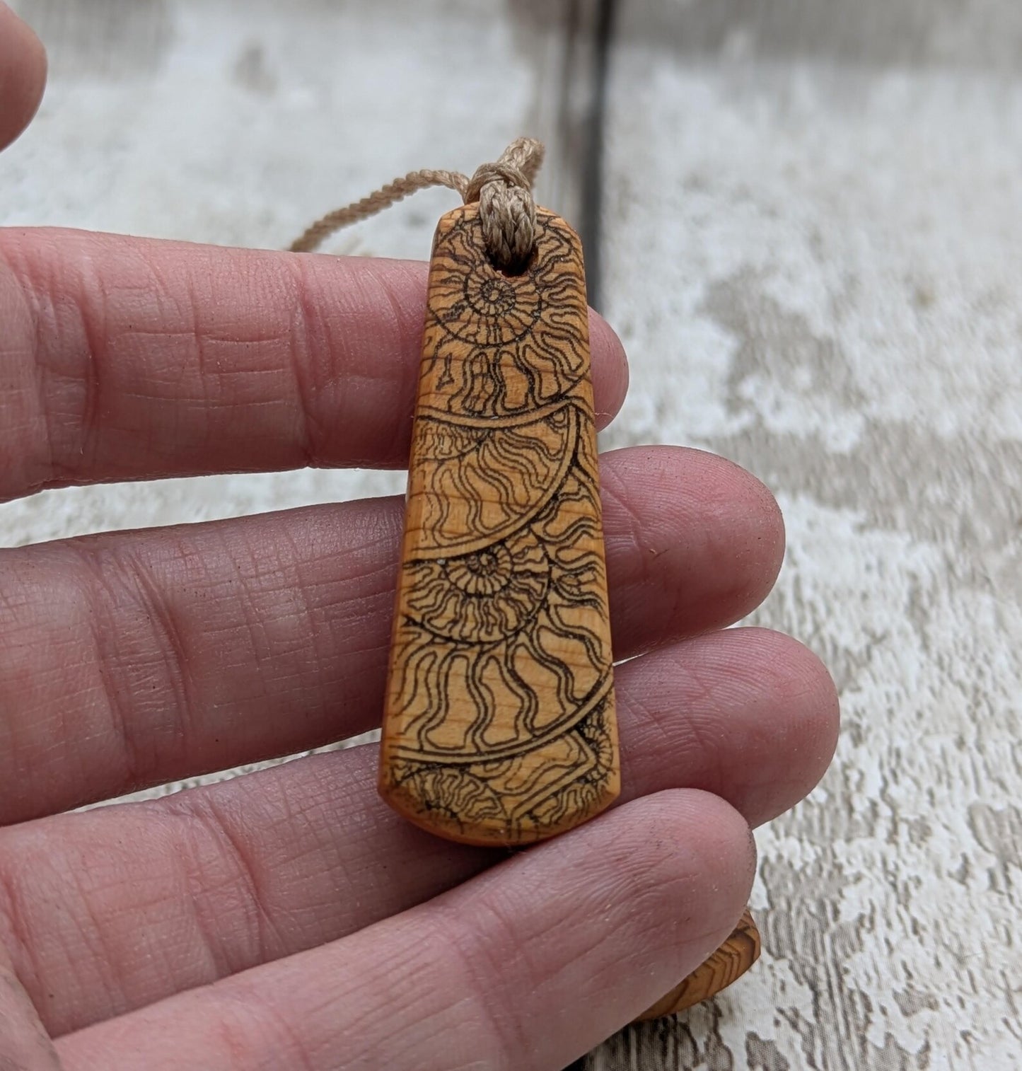 One Yew wood ammonite laser printed tear drop pendant.