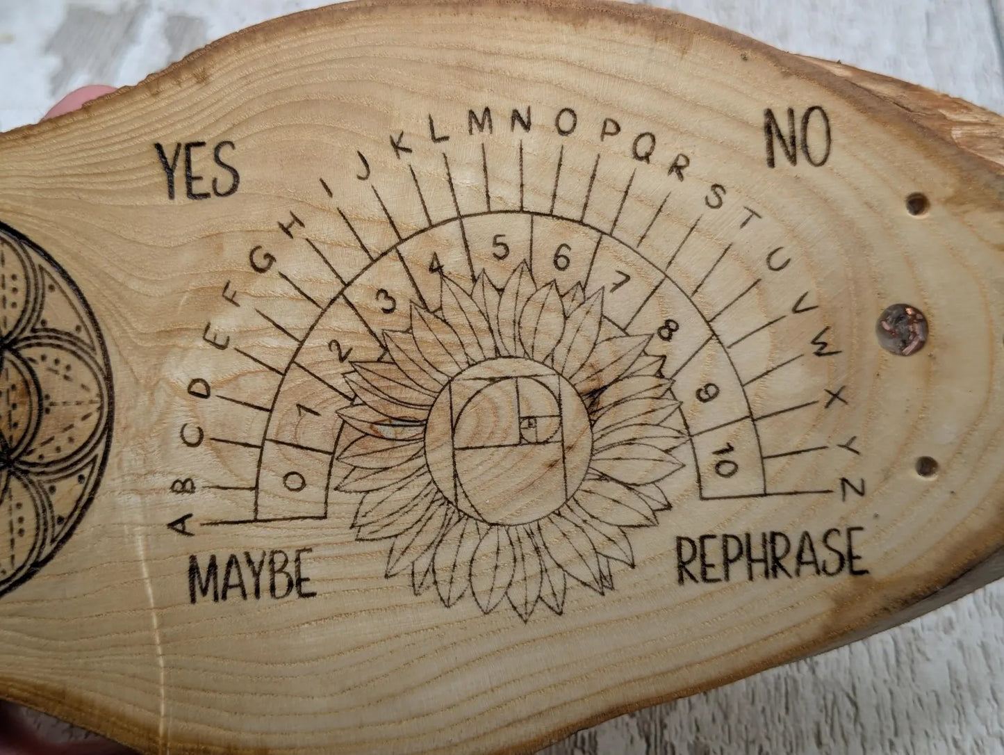 Ash wood laser printed pendulum dowsing board with sunflower detail.