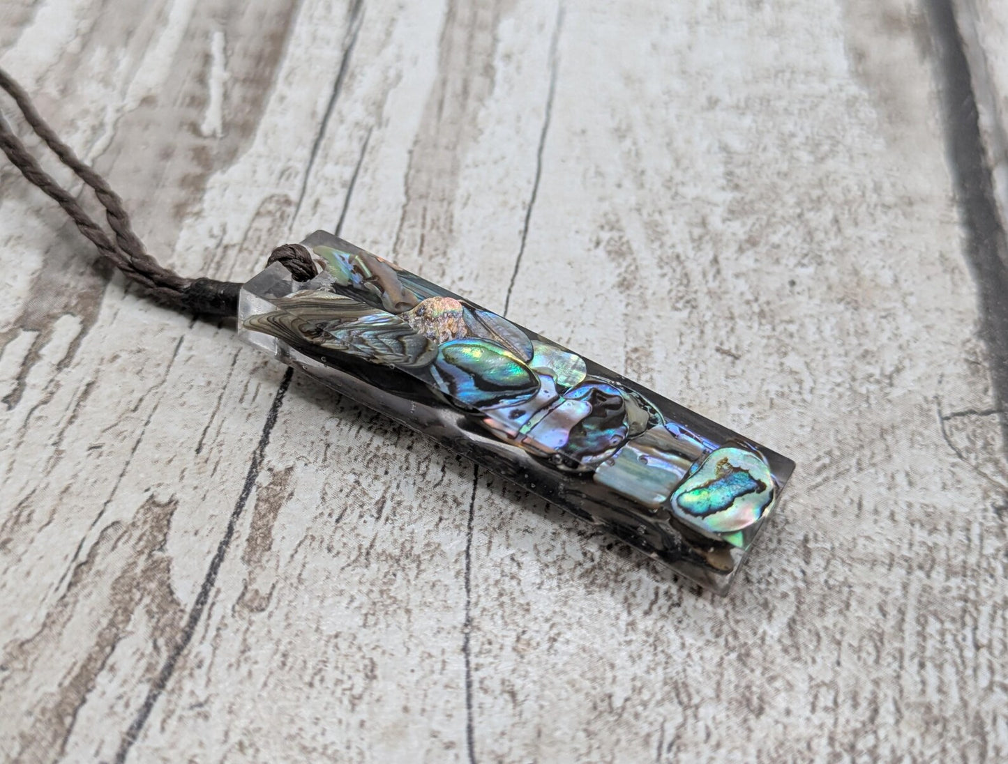 One New Zealand rainbow pāua chips in resin.