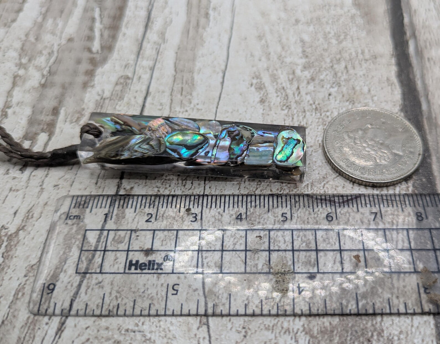 One New Zealand rainbow pāua chips in resin.