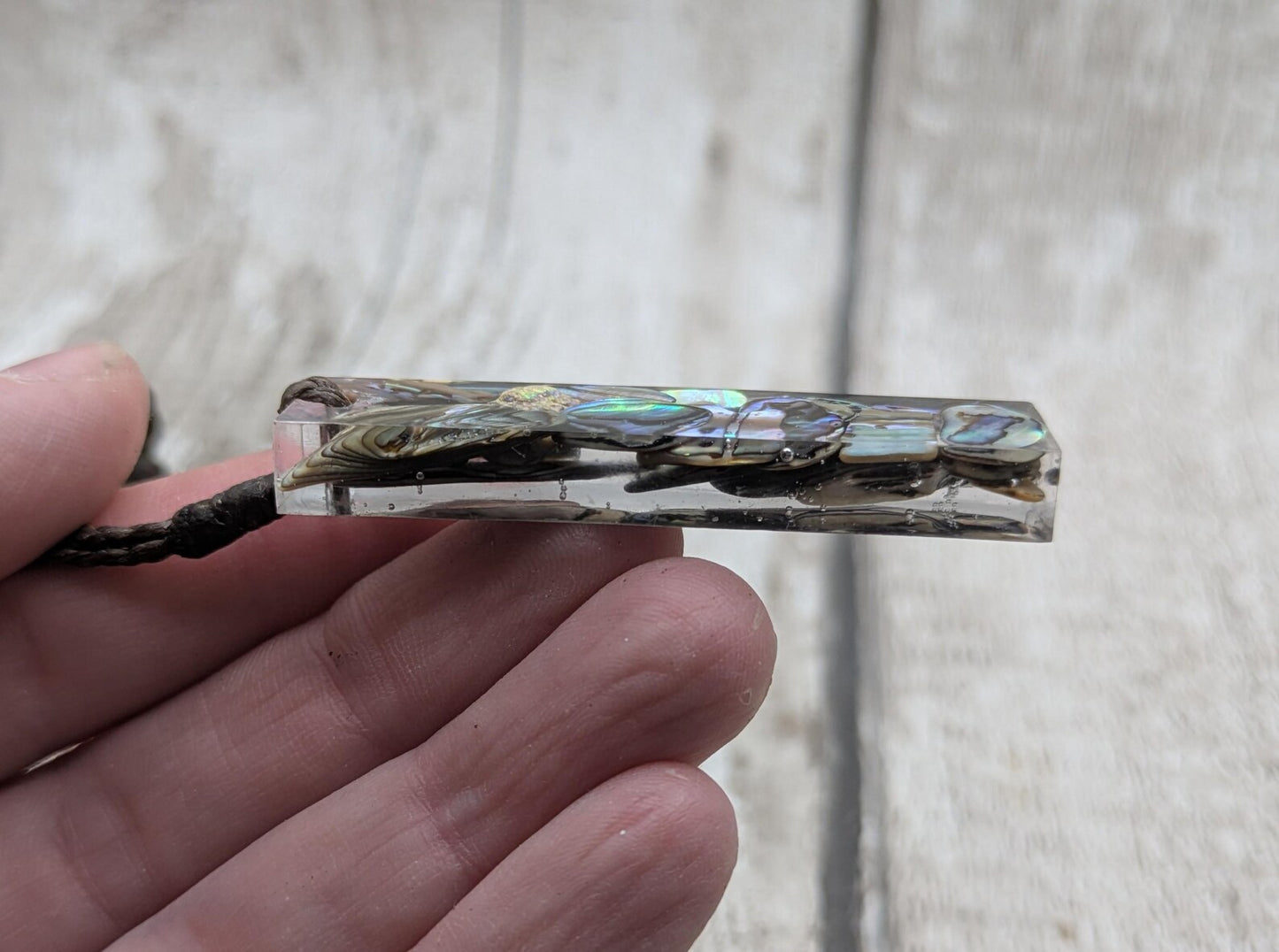 One New Zealand rainbow pāua chips in resin.