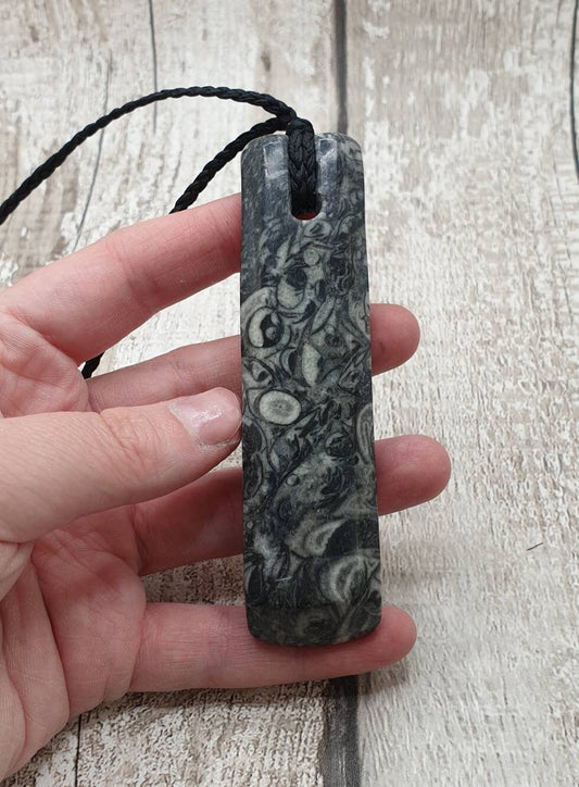 Orthoseras and goniatite fossil bed rock unisex toki pendant.