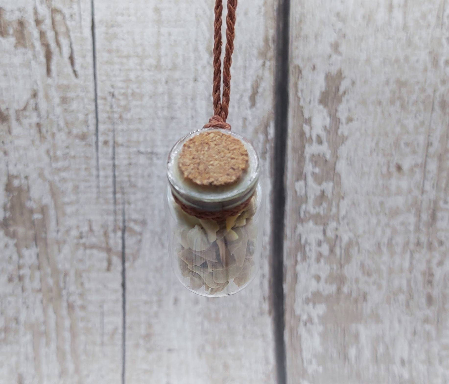 Fossilised sharks teeth glass bottle pendant.